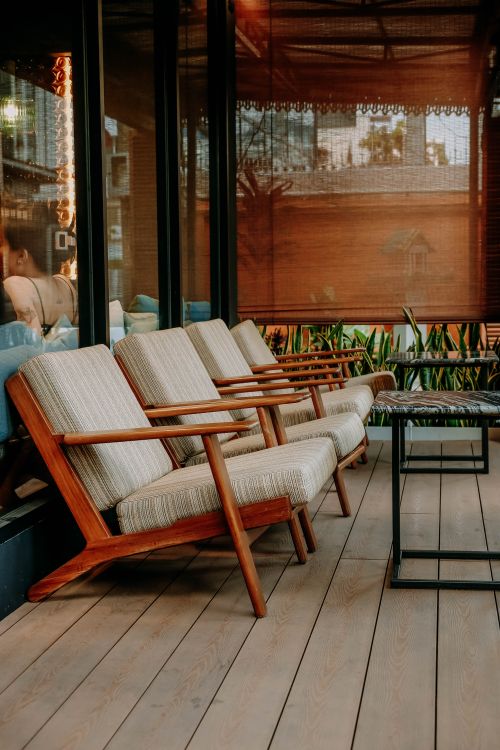 Free Stylish wooden chairs with cushions on a modern outdoor patio, perfect for relaxation. Stock Photo