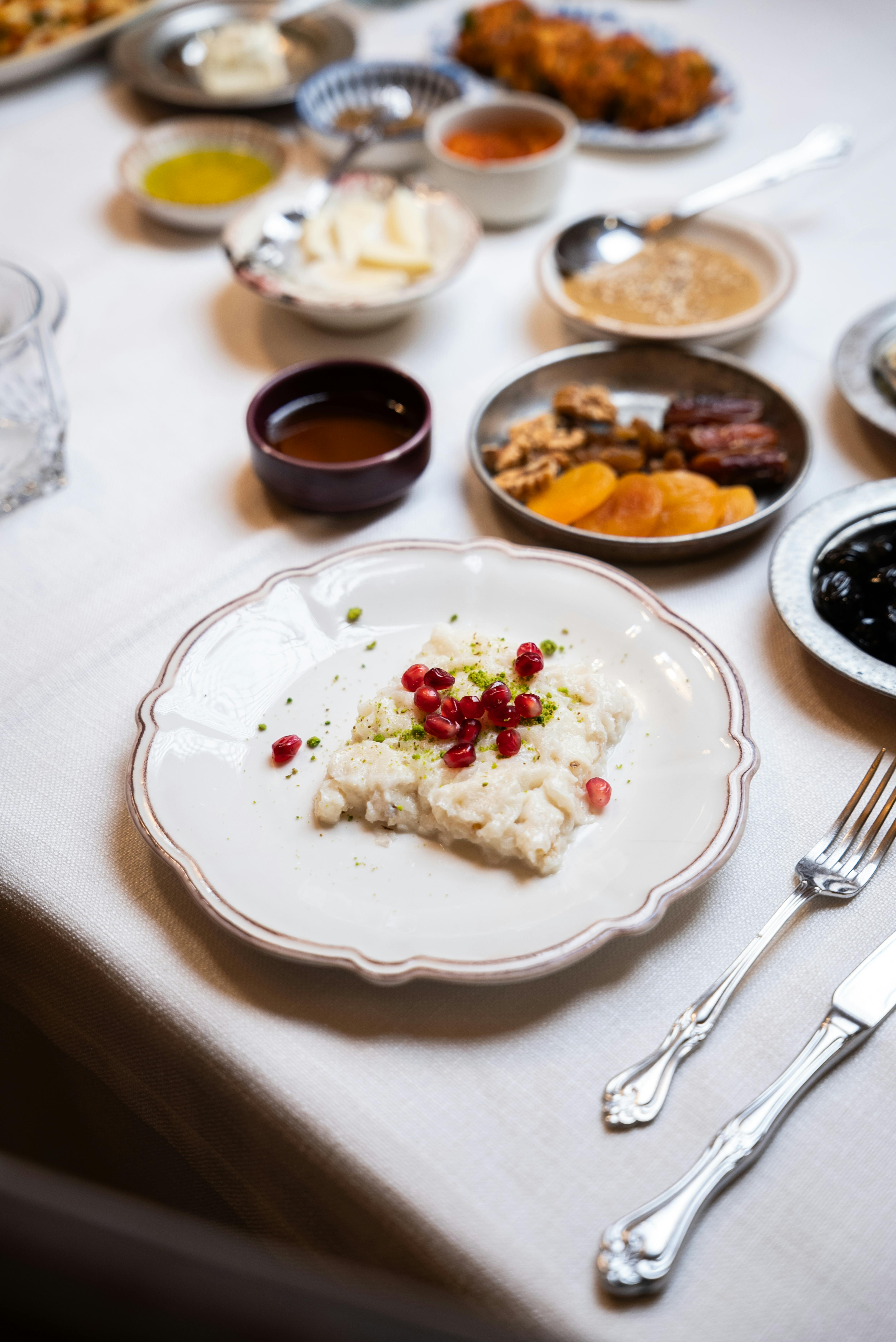 Kostenlos Ein wunderschön präsentierter türkischer Sütlaç, garniert mit Granatapfelkernen, auf einem eleganten Esstisch. Stock-Foto