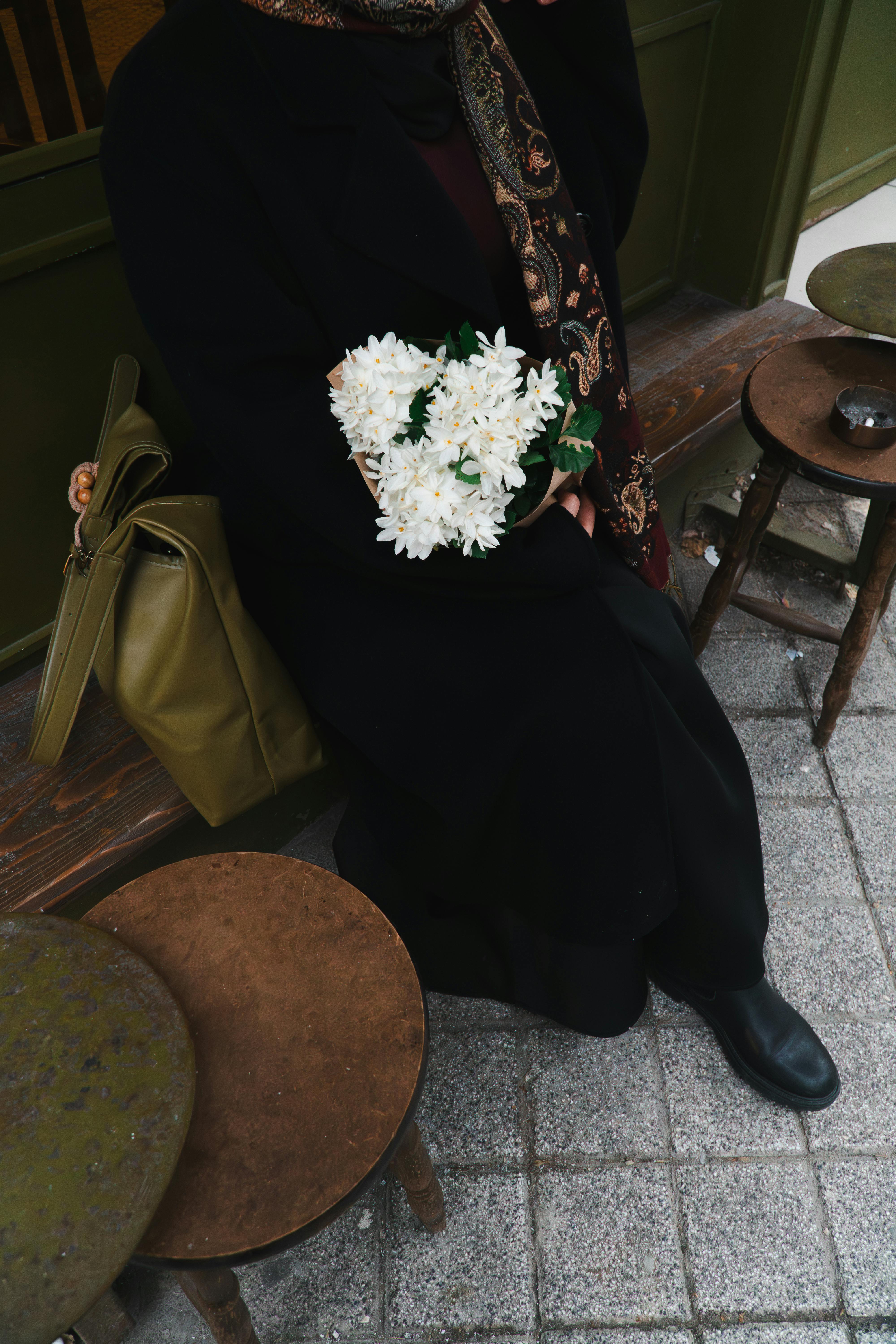 Free A person holding white flowers sitting outside a cafe in Istanbul. Stock Photo