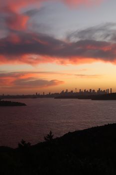 Breathtaking view of Sydney skyline with vivid sunset hues over the harbor, capturing the city's iconic beauty.