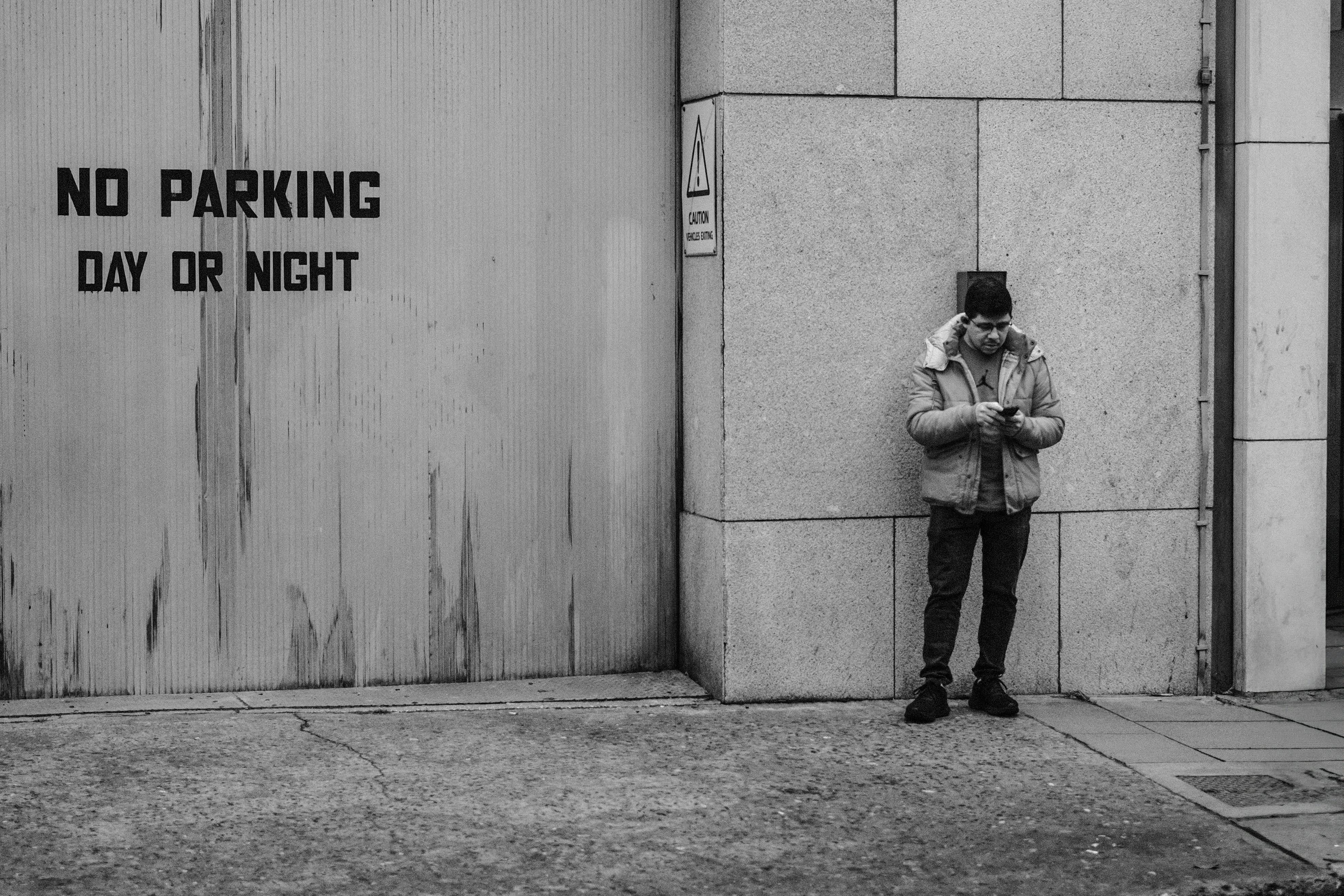 ฟรี ชายคนหนึ่งในชุดลำลองกำลังเช็คโทรศัพท์อยู่ข้างป้าย "ห้ามจอด" บนถนนในเมืองดับลิน คลังภาพถ่าย