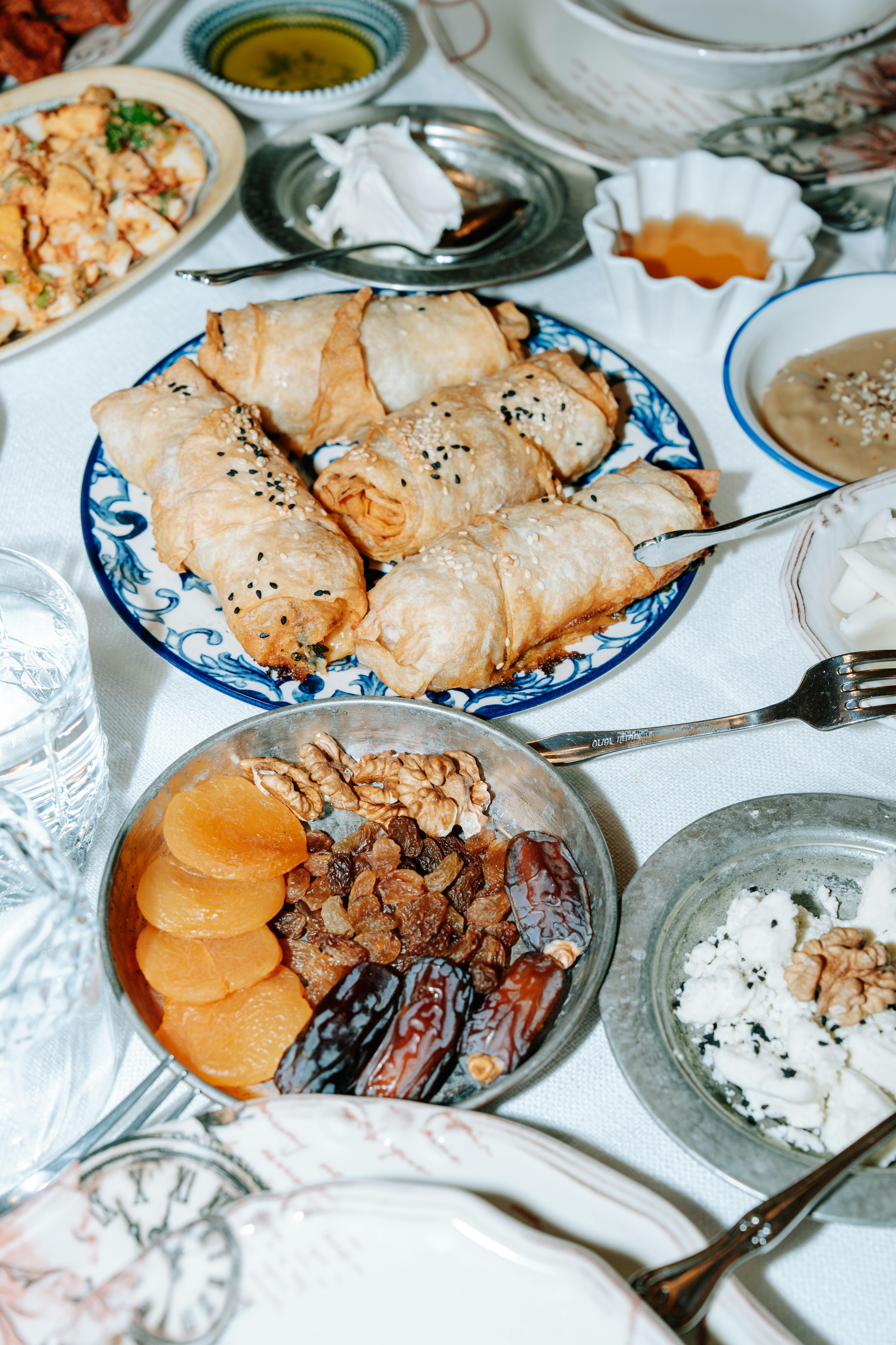 Gratuit Une table dressée avec des pâtisseries du Moyen-Orient, des fruits secs, des noix et des sauces sur une nappe blanche. Photos