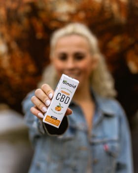 Focus on a woman presenting Binoid CBD oil with an autumn background. Promotes wellness and health.
