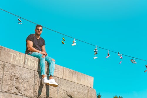Free Low-angle Photography of Man Sitting on Pavement Under Blue Sky Stock Photo