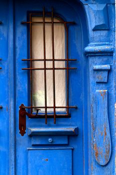 A weathered blue wooden door featuring a vintage iron grille design.