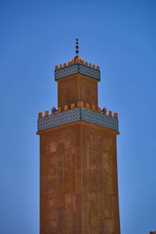 Free A stunning view of a Moroccan minaret with intricate designs against a vivid blue sky. Stock Photo