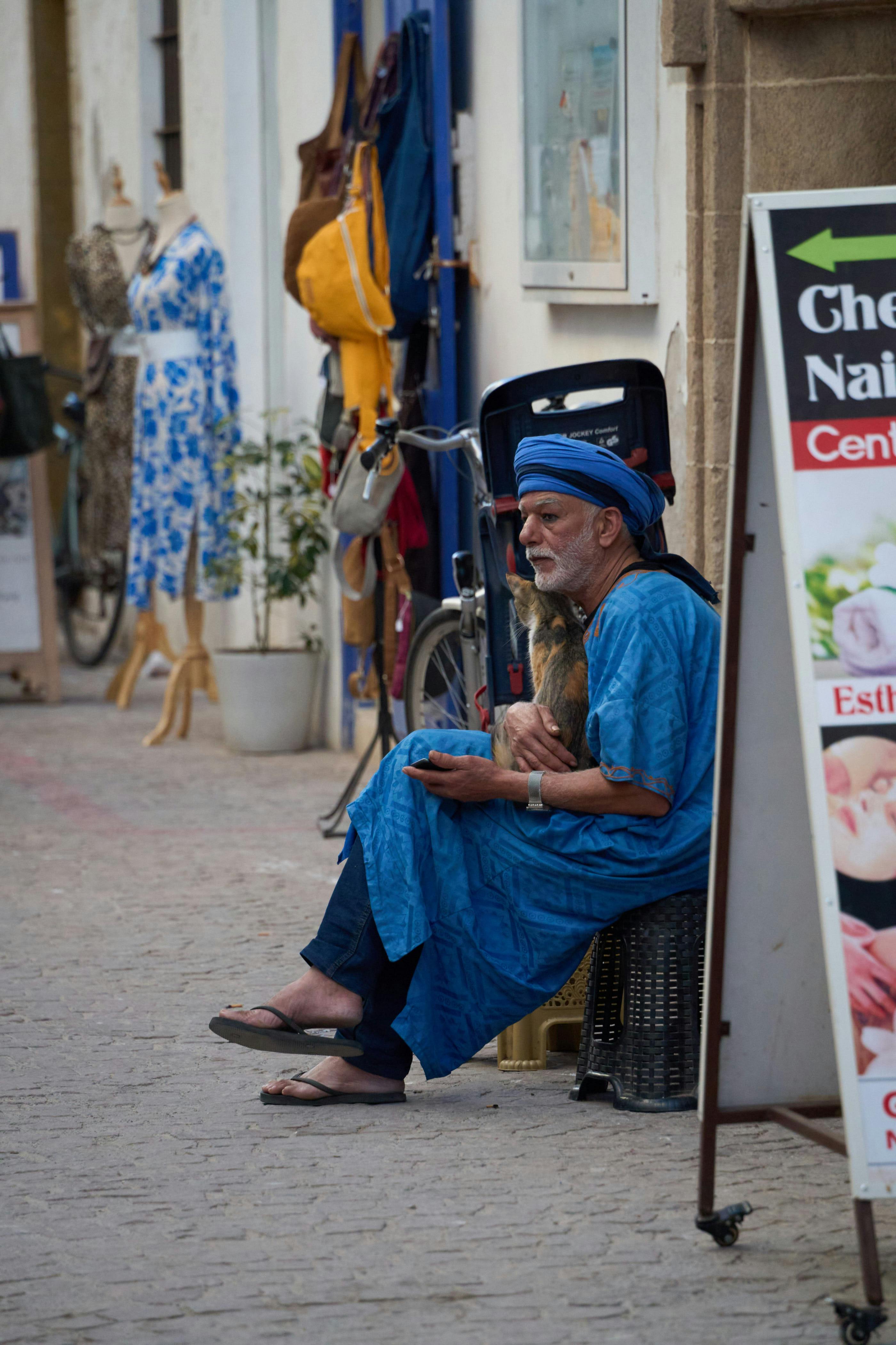 bezplatná Starší muž oblečený v tradičním marockém oděvu sedí na ulici v Marruecos. Základová fotografie