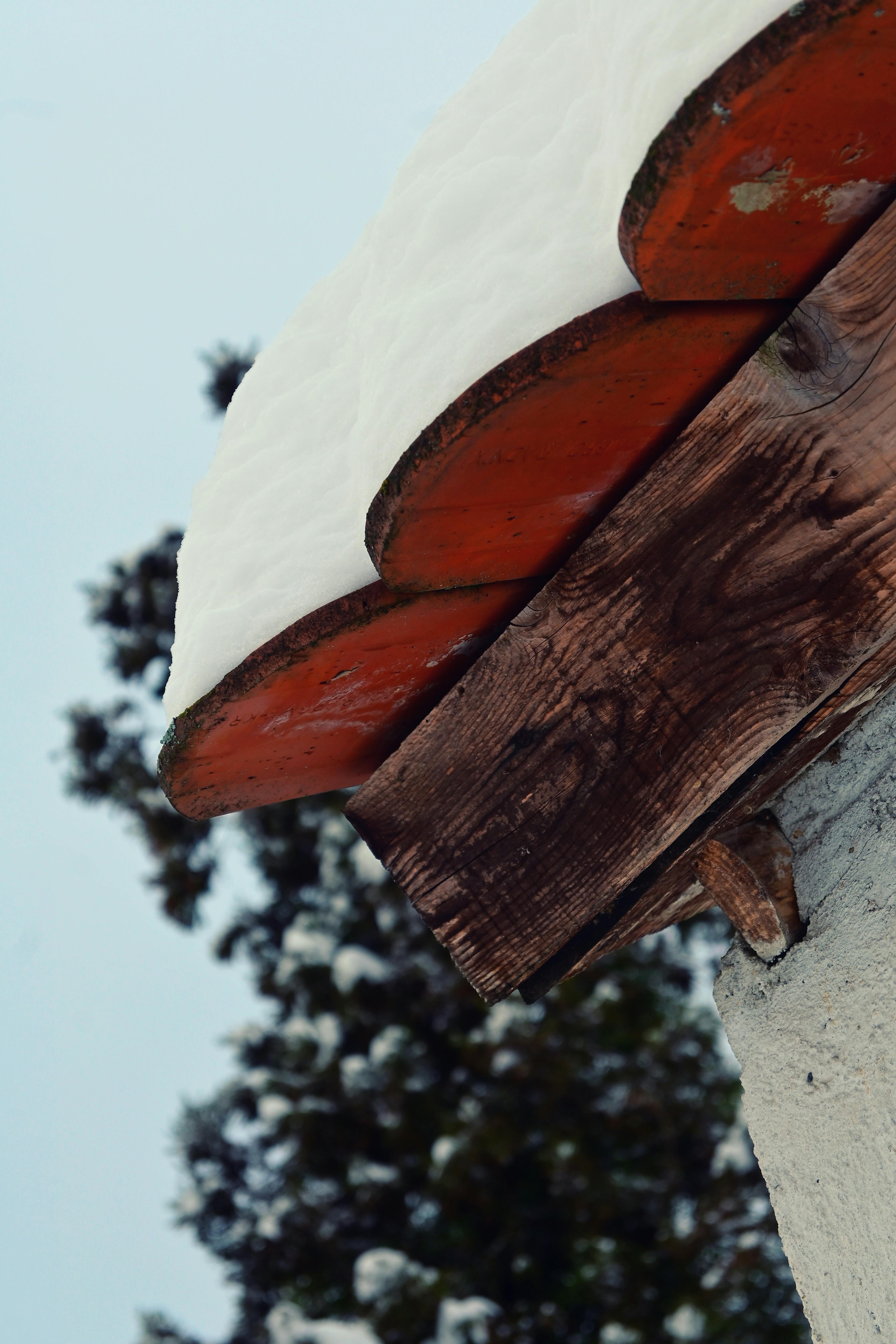 Zadarmo Detailný záber na rustikálny zasnežený okraj strechy so zimným pozadím. Fotka z fotobanky