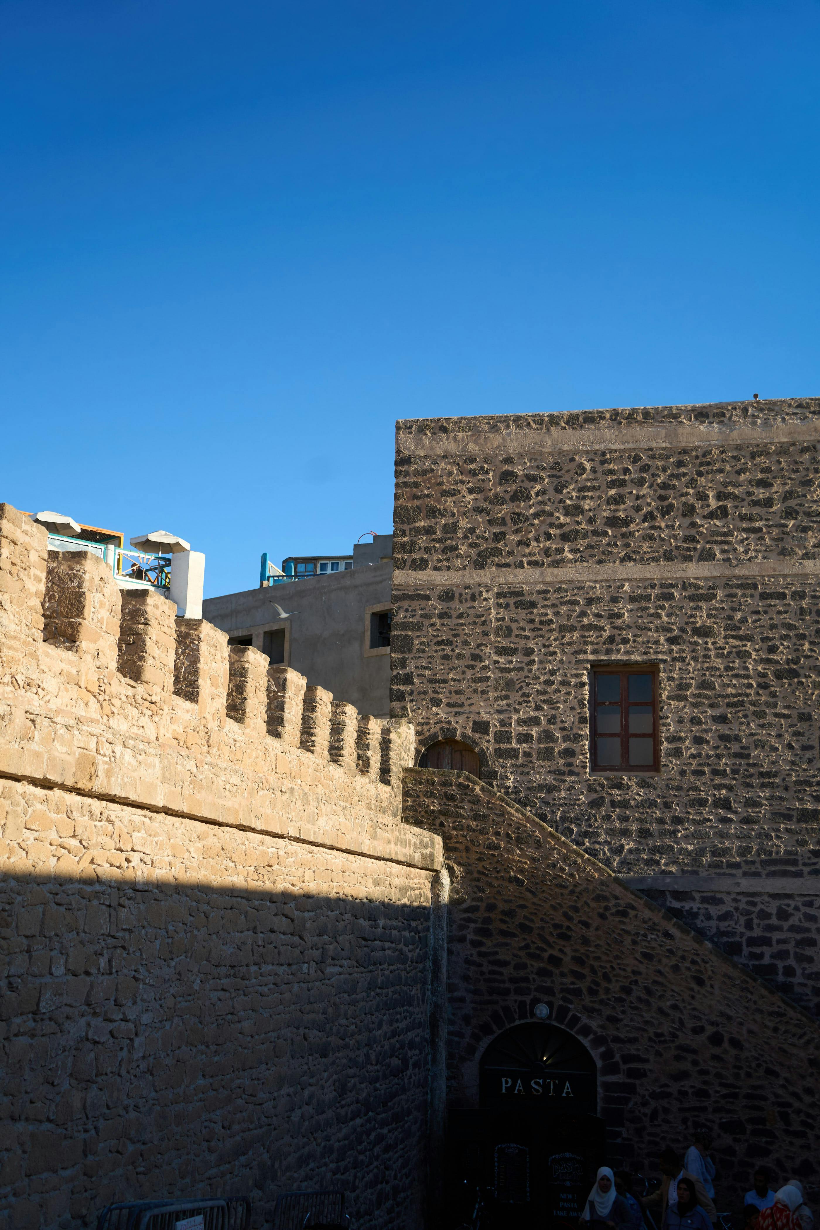 Miễn phí Cảnh quan nhìn từ trên cao xuống những mặt tiền và bức tường đá cổ kính ở Essaouira, Morocco, dưới bầu trời xanh trong vắt. Ảnh lưu trữ