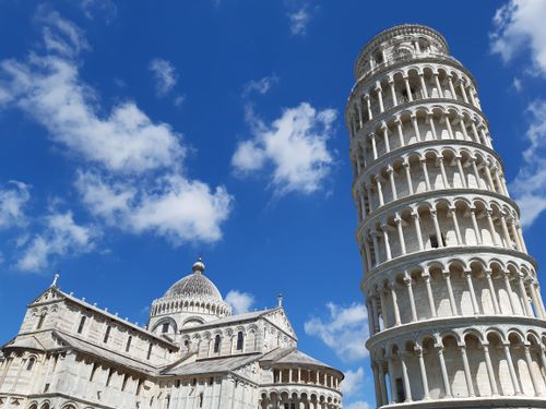 Free Stunning view of the Leaning Tower of Pisa against a vibrant blue sky with fluffy clouds. Stock Photo
