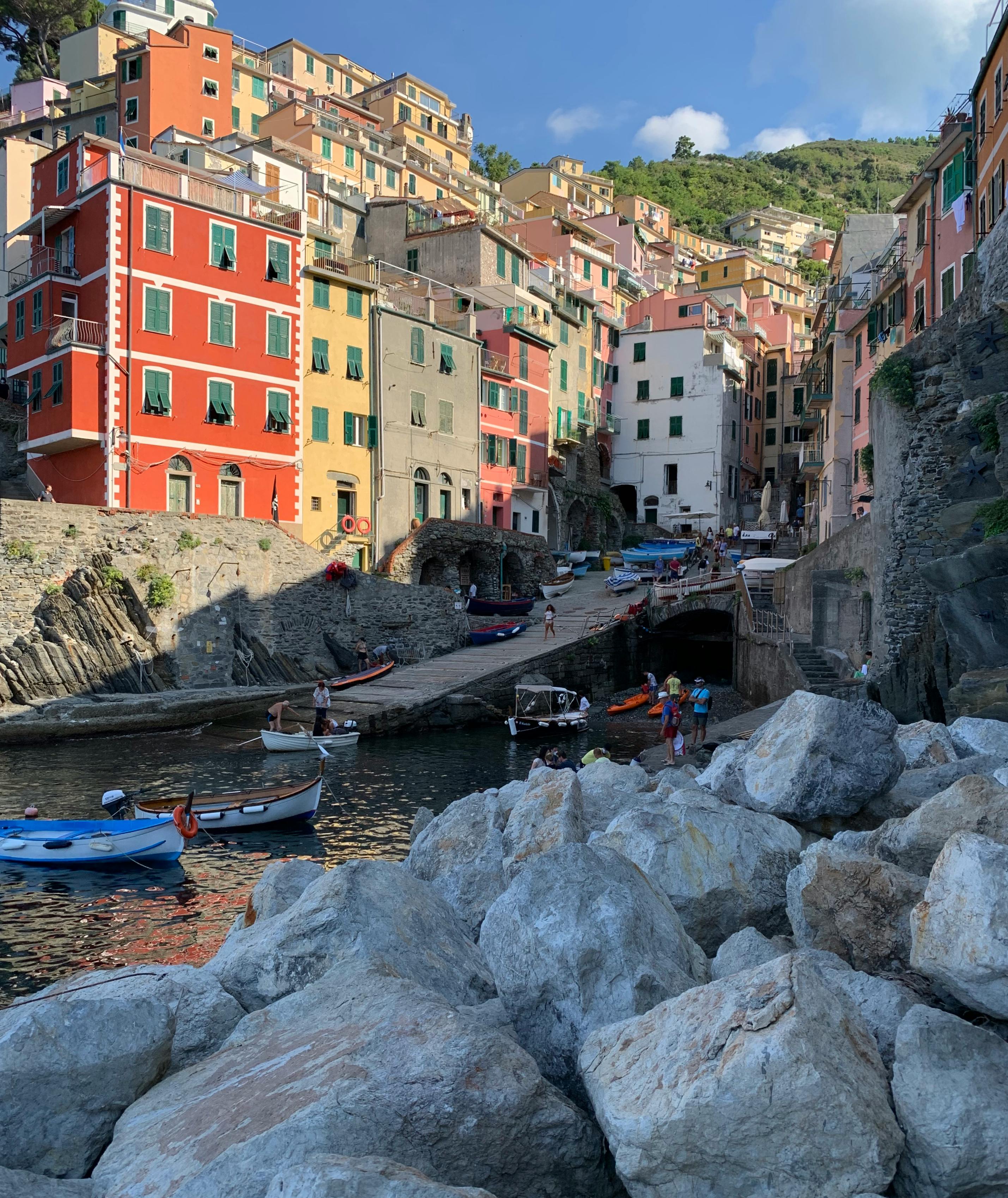 Free A vibrant seaside village in Riomaggiore, Italy features colorful buildings by the rocky harbor. Stock Photo