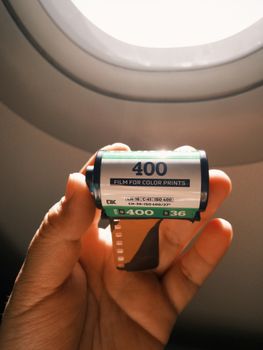 Close-up of a 400 ISO film roll held up against an airplane window in warm light.