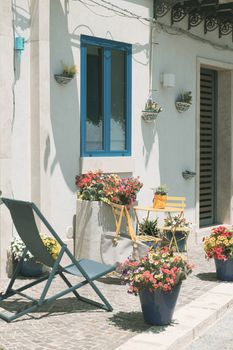 Cozy outdoor patio in Venice with vibrant flowers, blue window details, and seating area.