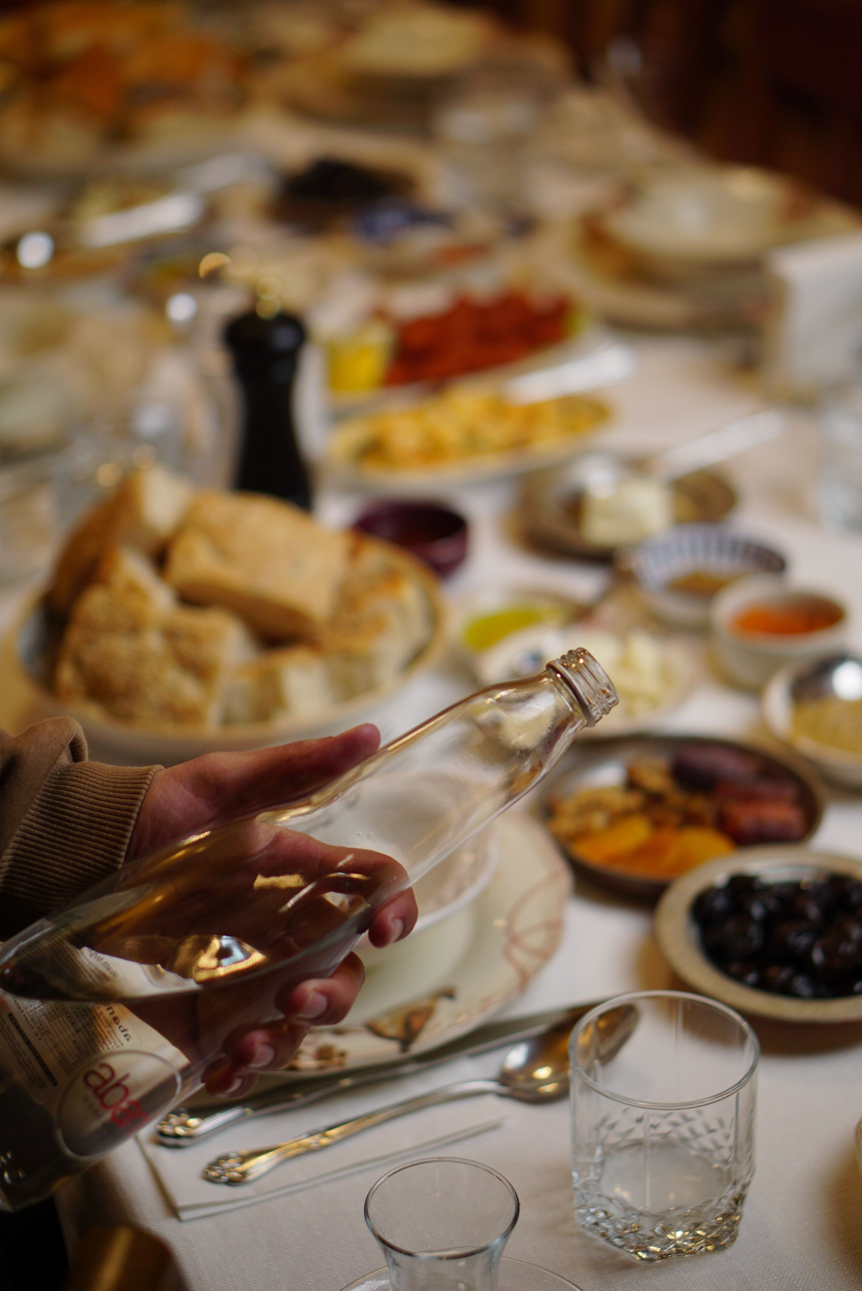 Ücretsiz Bir elin şişe tuttuğu ve çeşitli yiyeceklerle dolu şenlikli bir yemek masasının yakın çekim görüntüsü. Stok Fotoğraflar