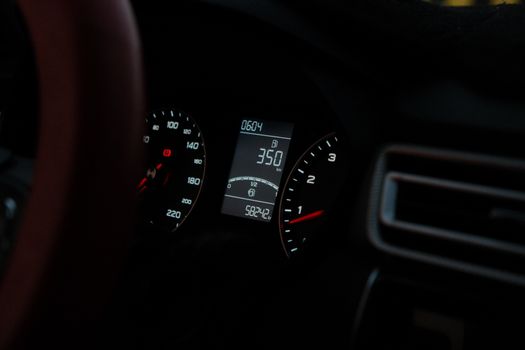 Car dashboard showing speedometer and digital readout at night. Perfect for automotive or technology themes.