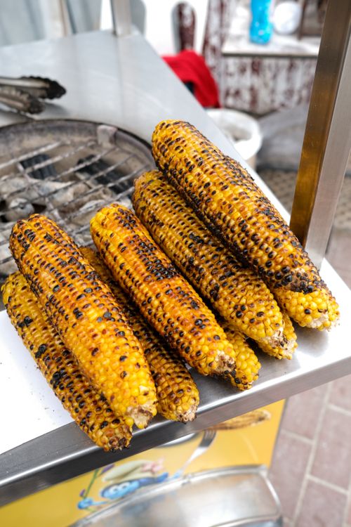 Free Delicious grilled corn stacked on a street vendor's cart, perfect snack. Stock Photo