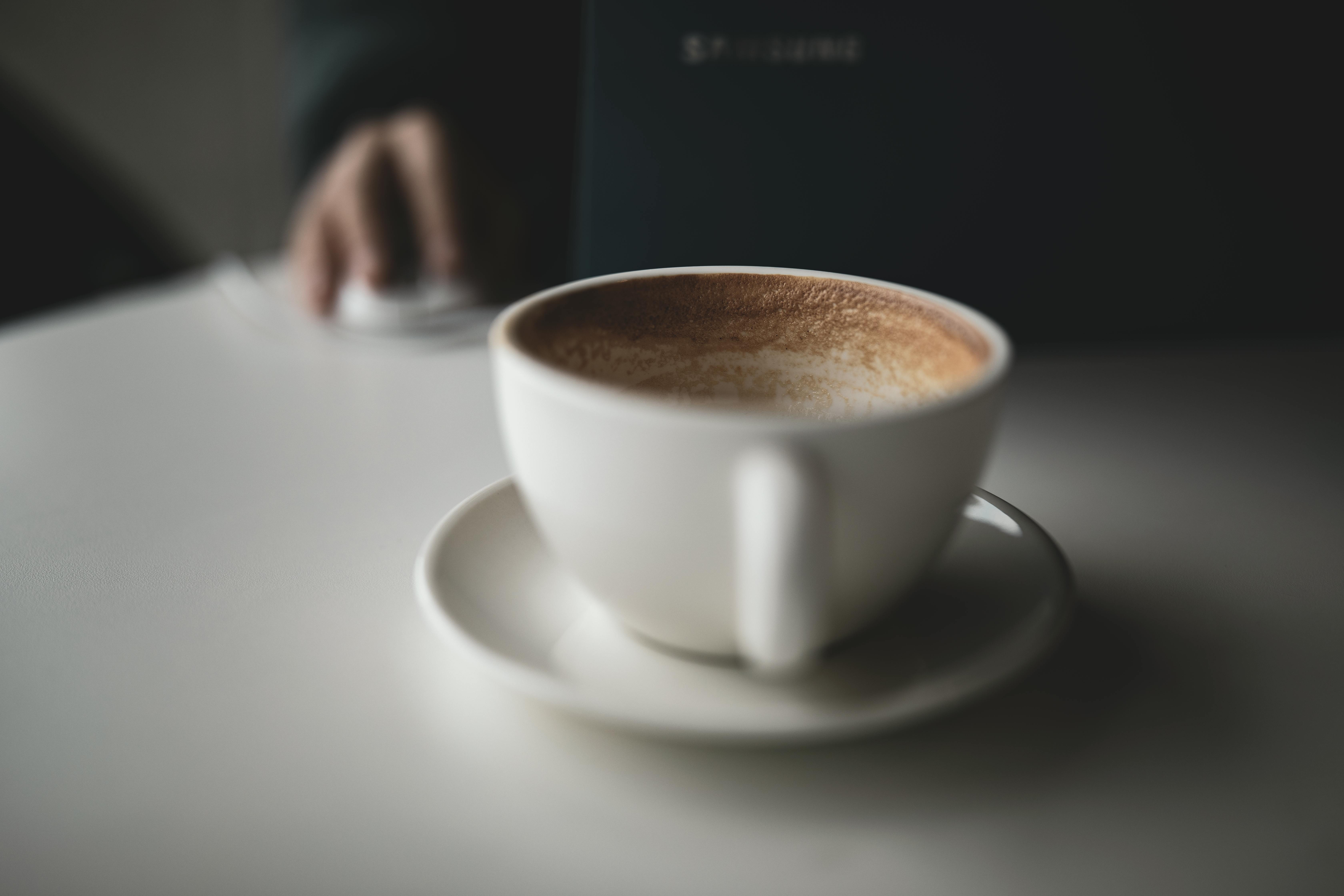 Zadarmo Biely šálka latte na stole vedľa notebooku, naznačujúci prácu alebo štúdium. Fotka z fotobanky