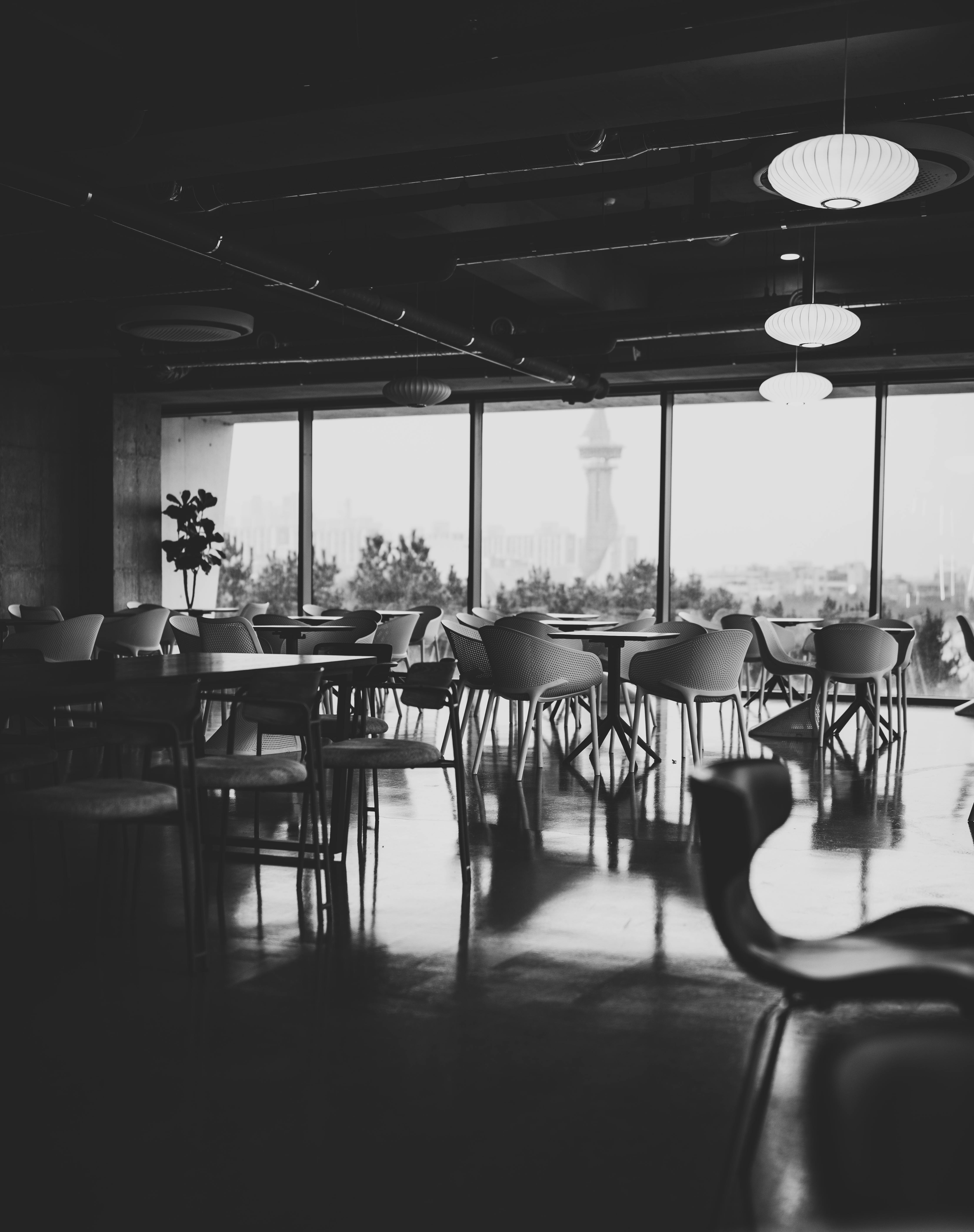 Zadarmo Elegantný čiernobiely interiér kaviarne s vyzdvihnutím miesta na sedenie a výhľadom na panorámu mesta cez veľké okná. Fotka z fotobanky