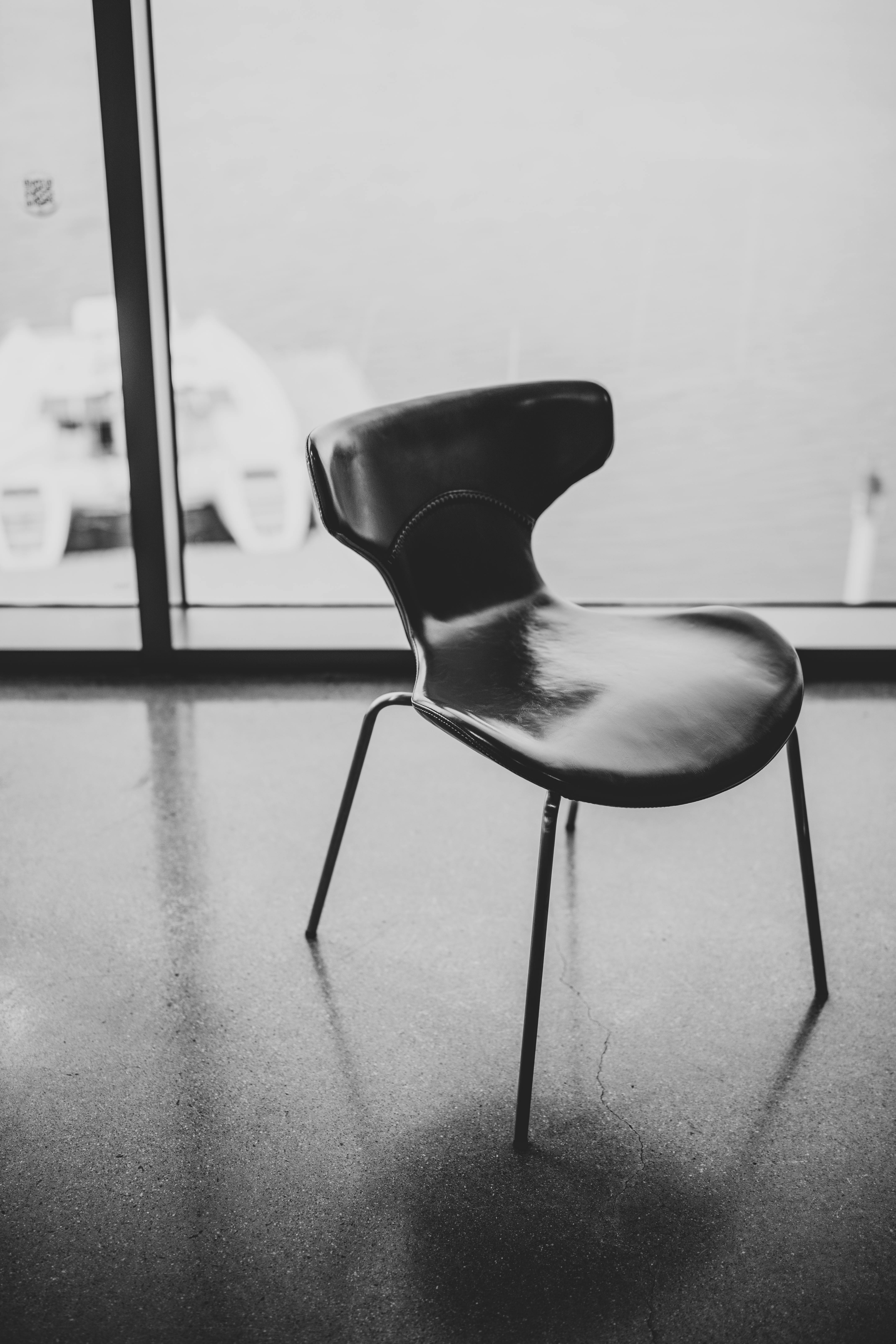 ingyenes Fekete szék egy üres szobában, nagy ablakokkal, kilátással a vízre. Elegáns design. Stockfotó