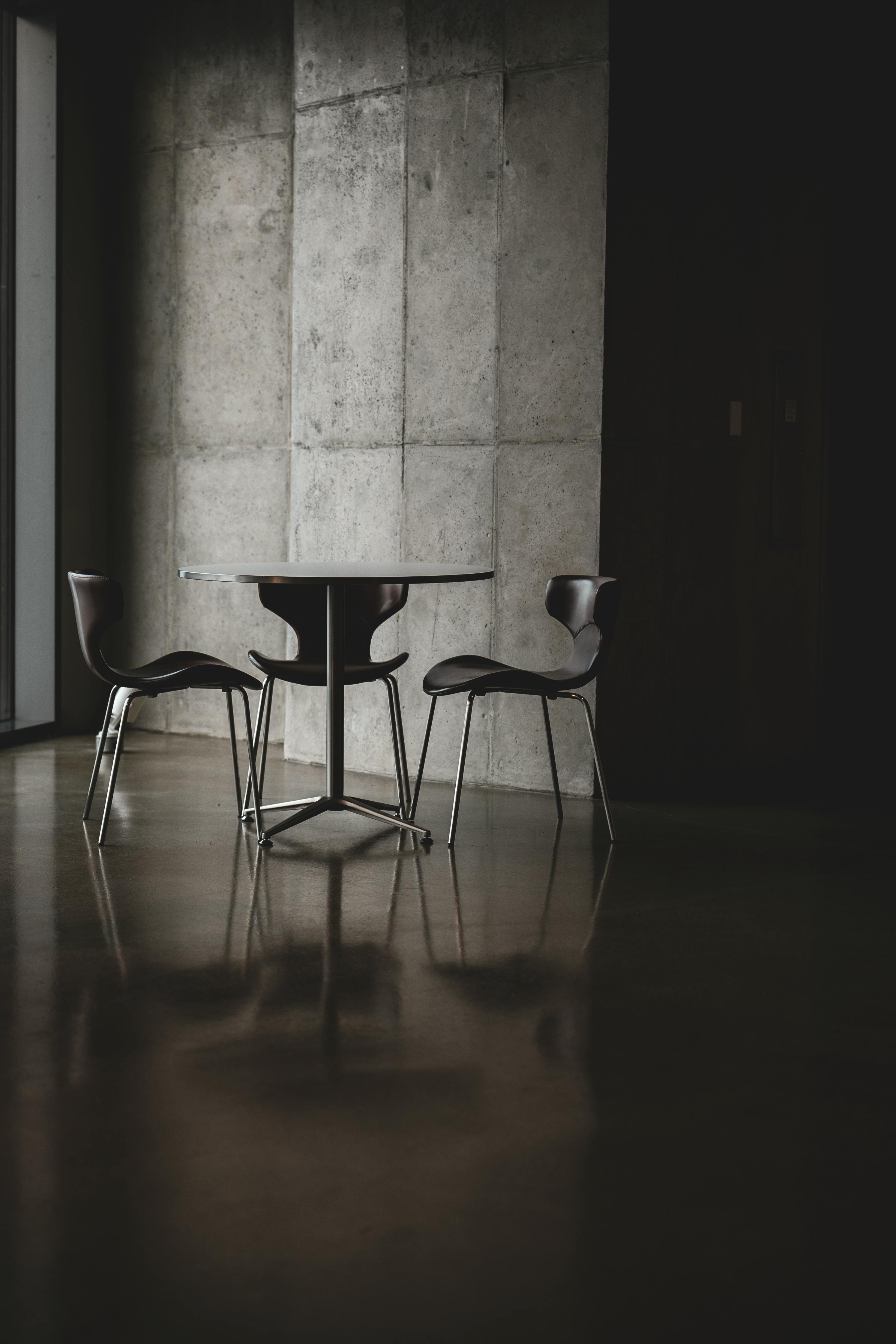 bezplatná Stylový minimalistický interiér se dvěma židlemi a stolem u betonové zdi. Základová fotografie