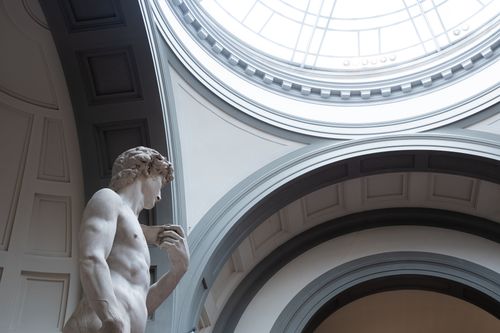 Free Side view of Michelangelo's David statue inside Florence's Accademia Gallery under a skylight. Stock Photo