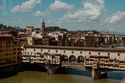 Free View of Ponte Vecchio and Florence's historic skyline under a vibrant sky. Stock Photo