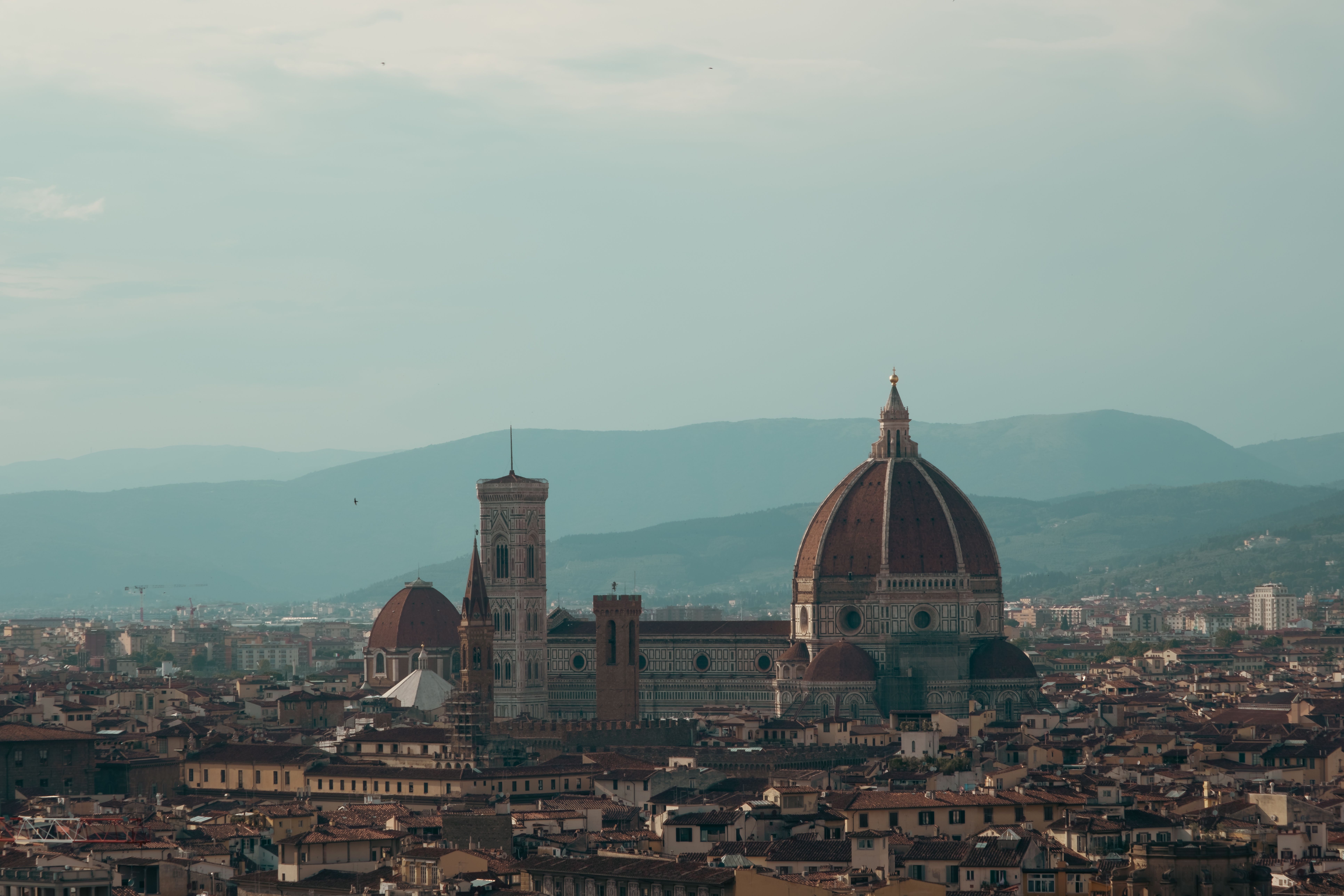 Florence Cathedral and its red-tiled dome rise above the city skyline, with hills in the distance