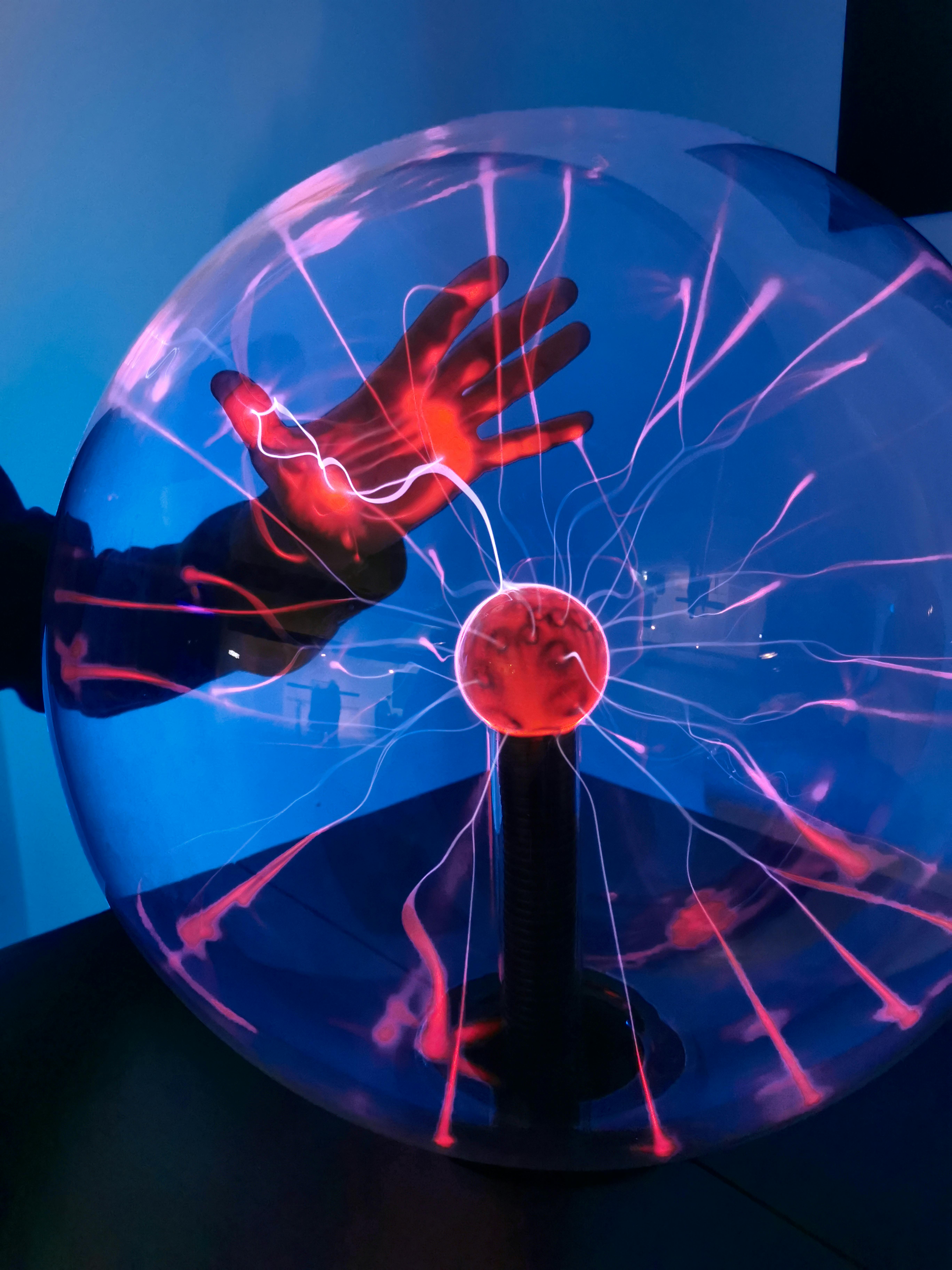 gratis Een fascinerende scène van een hand die interactie heeft met een verlichte plasmabol die levendige lichtpatronen uitzendt. Stockfoto