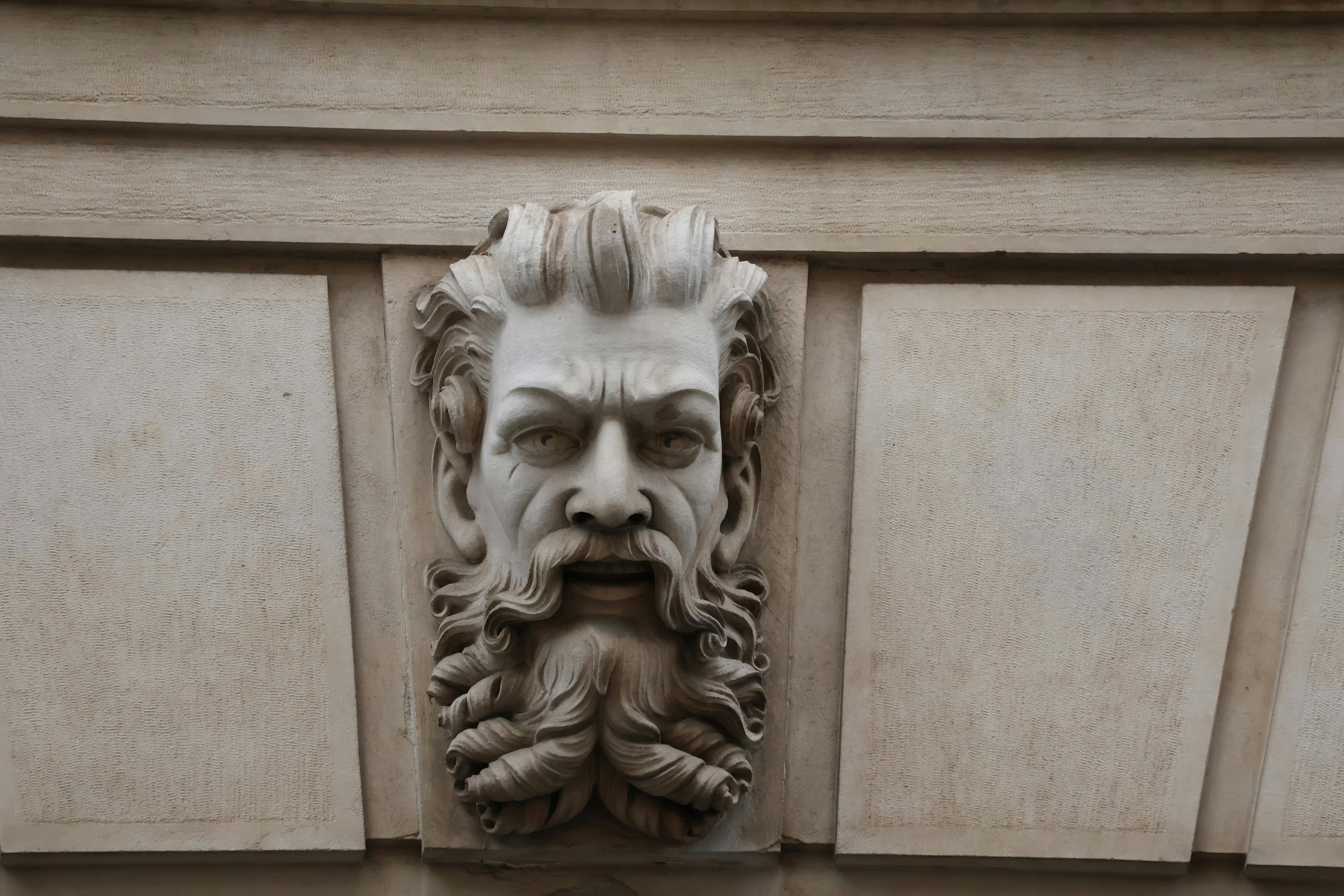 gratis Detailopname van een sierlijk bewerkte stenen gezichtssculptuur, gemonteerd op een buitenmuur. Stockfoto