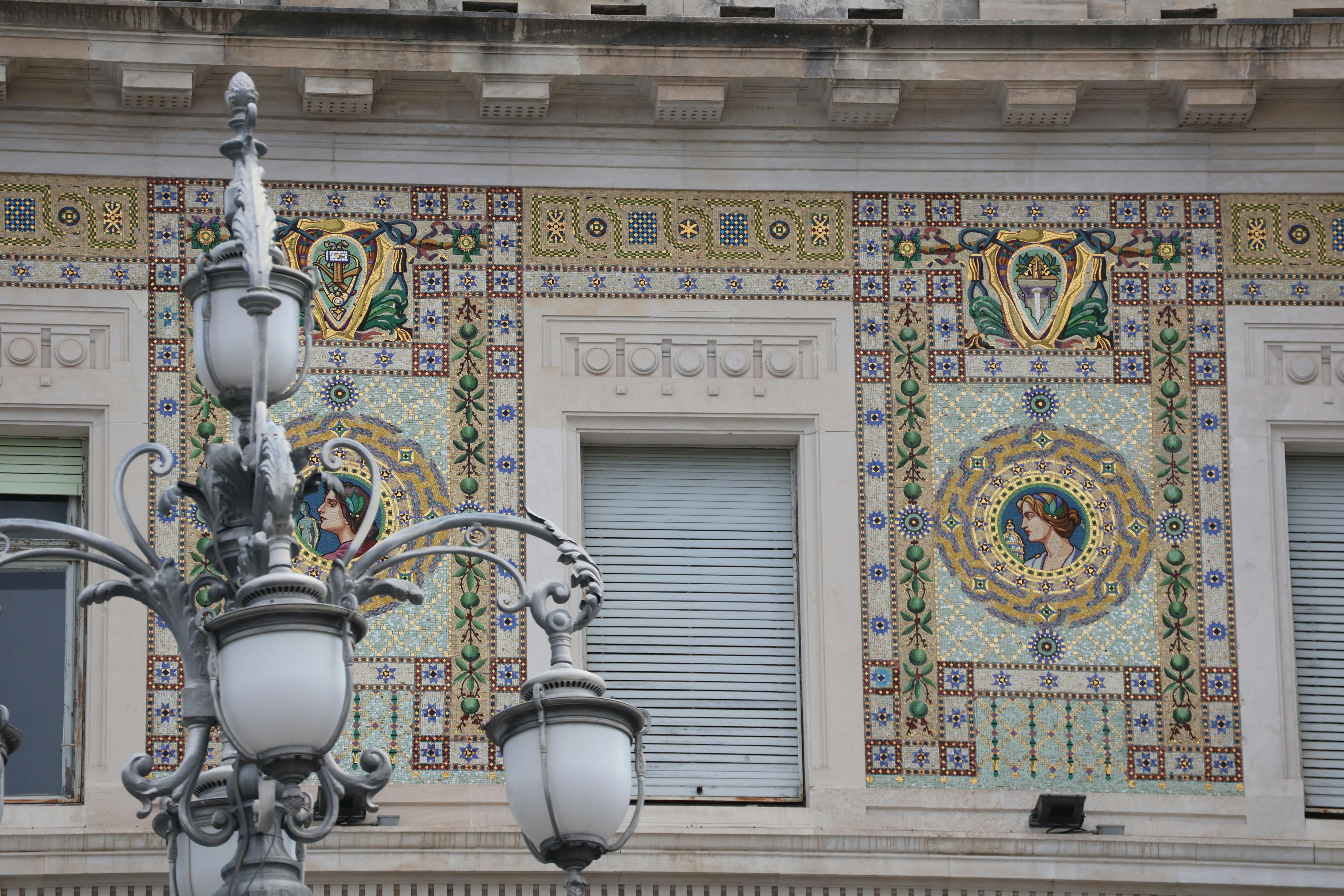 Gratis Intrincados mosaicos de cerámica adornan la fachada de un edificio histórico con farolas de época. Foto de stock