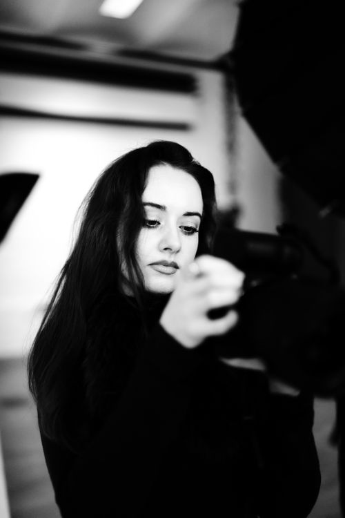 Free Artistic black and white photo of a woman engaging with camera equipment indoors. Stock Photo
