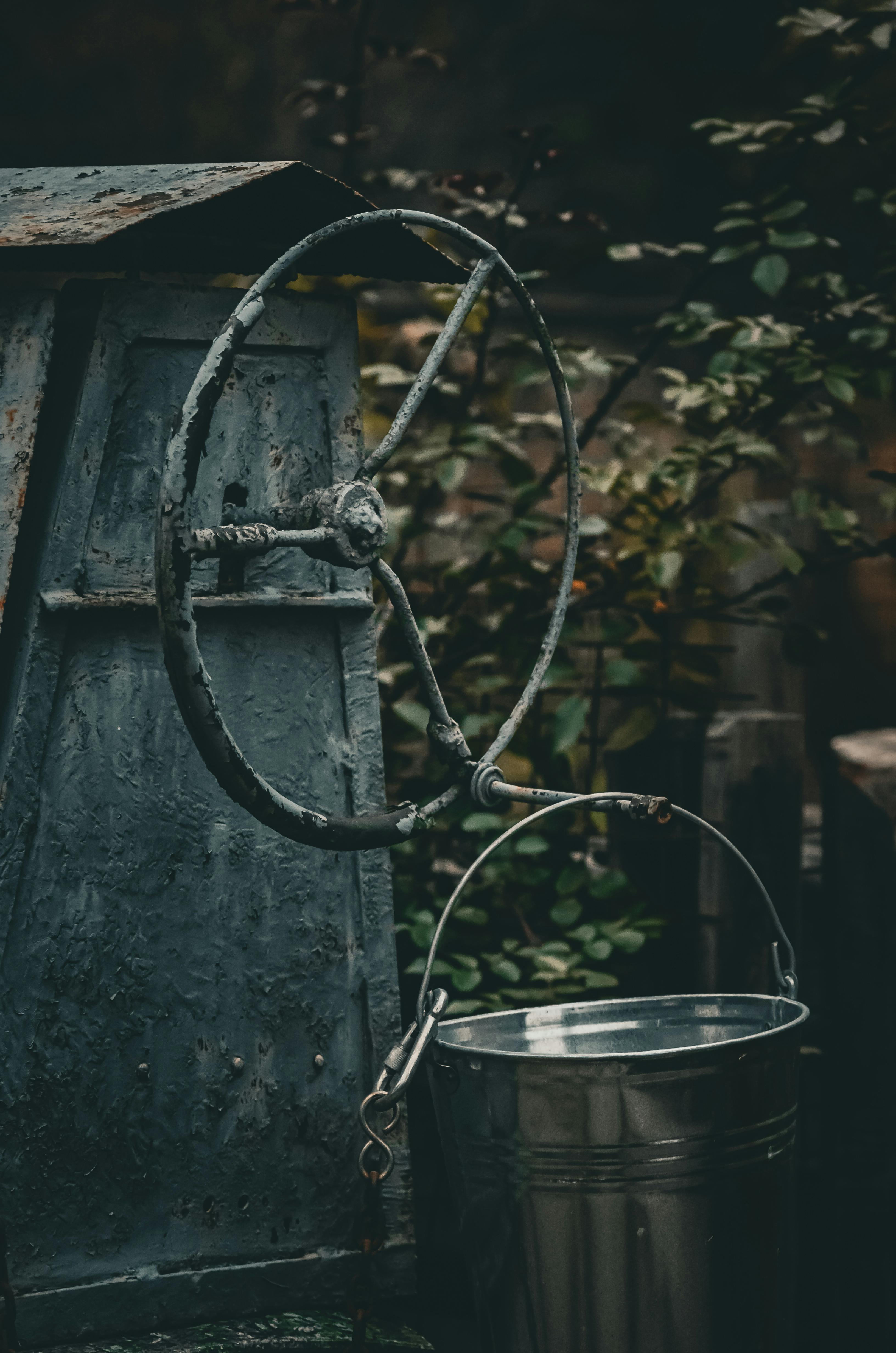 Zadarmo Rustikálne studňové čerpadlo s kovovým vedrom vo vidieckom záhradnom prostredí na Ukrajine s vintage a zemitými tónmi. Fotka z fotobanky