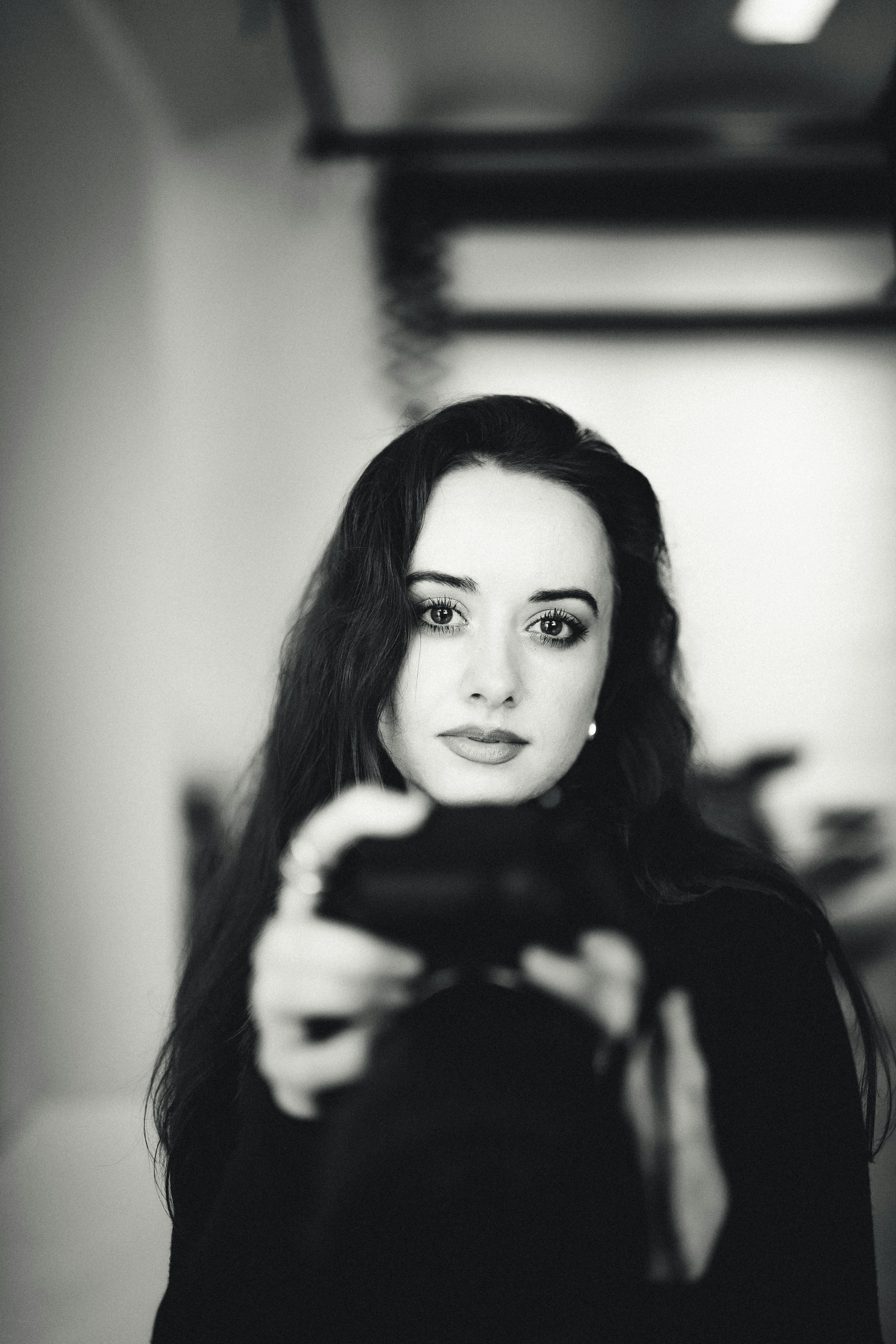 Elegant black and white portrait of a woman holding a camera indoors.