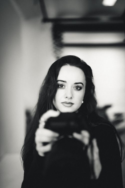 Free Elegant black and white portrait of a woman holding a camera indoors. Stock Photo