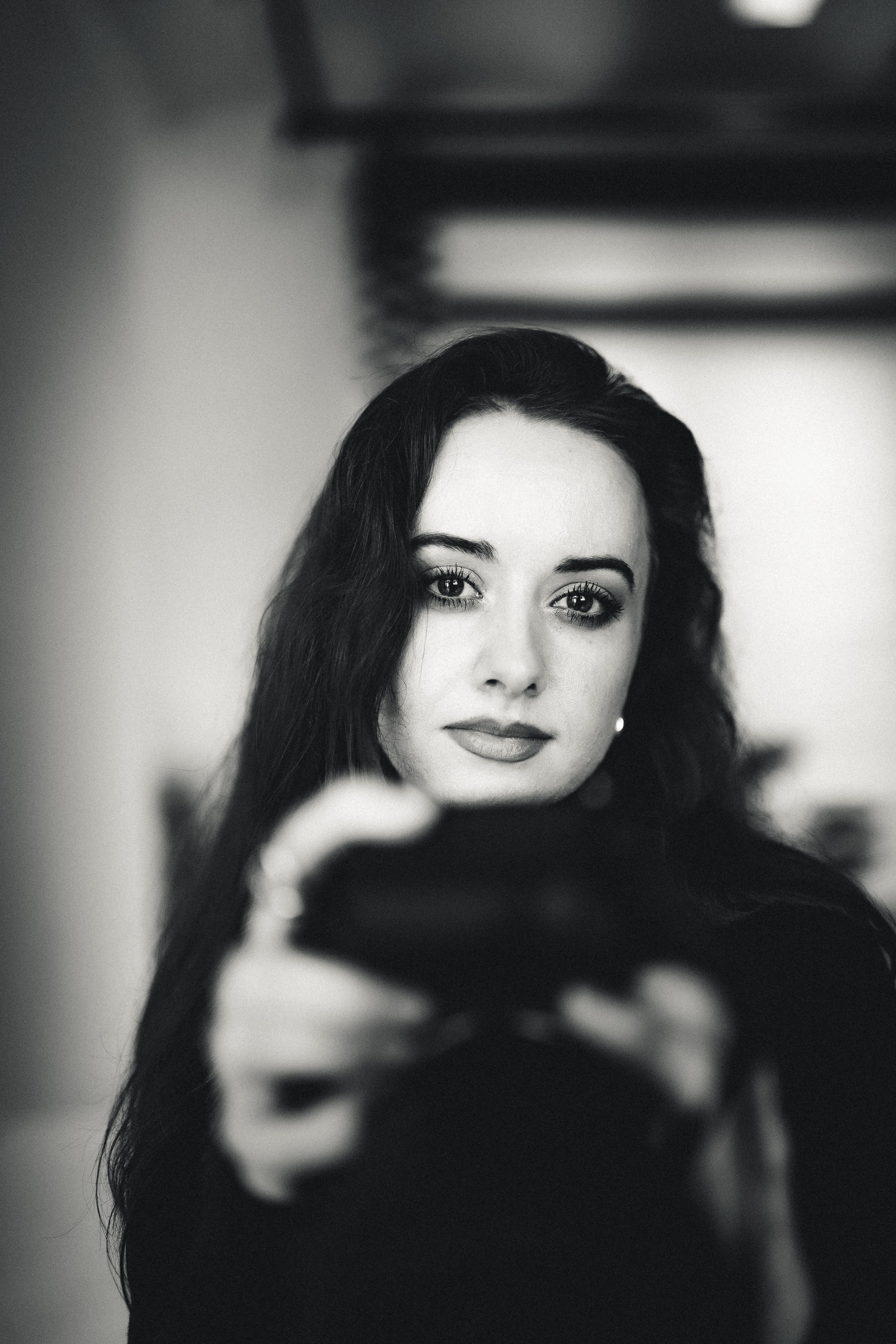 Portrait of a woman gazing at the camera in a moody, black and white setting.