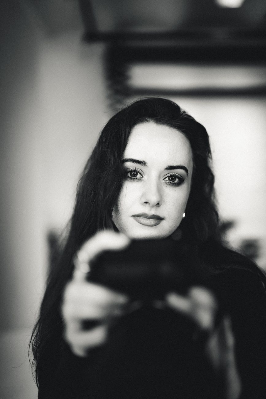 Portrait of a woman gazing at the camera in a moody, black and white setting.