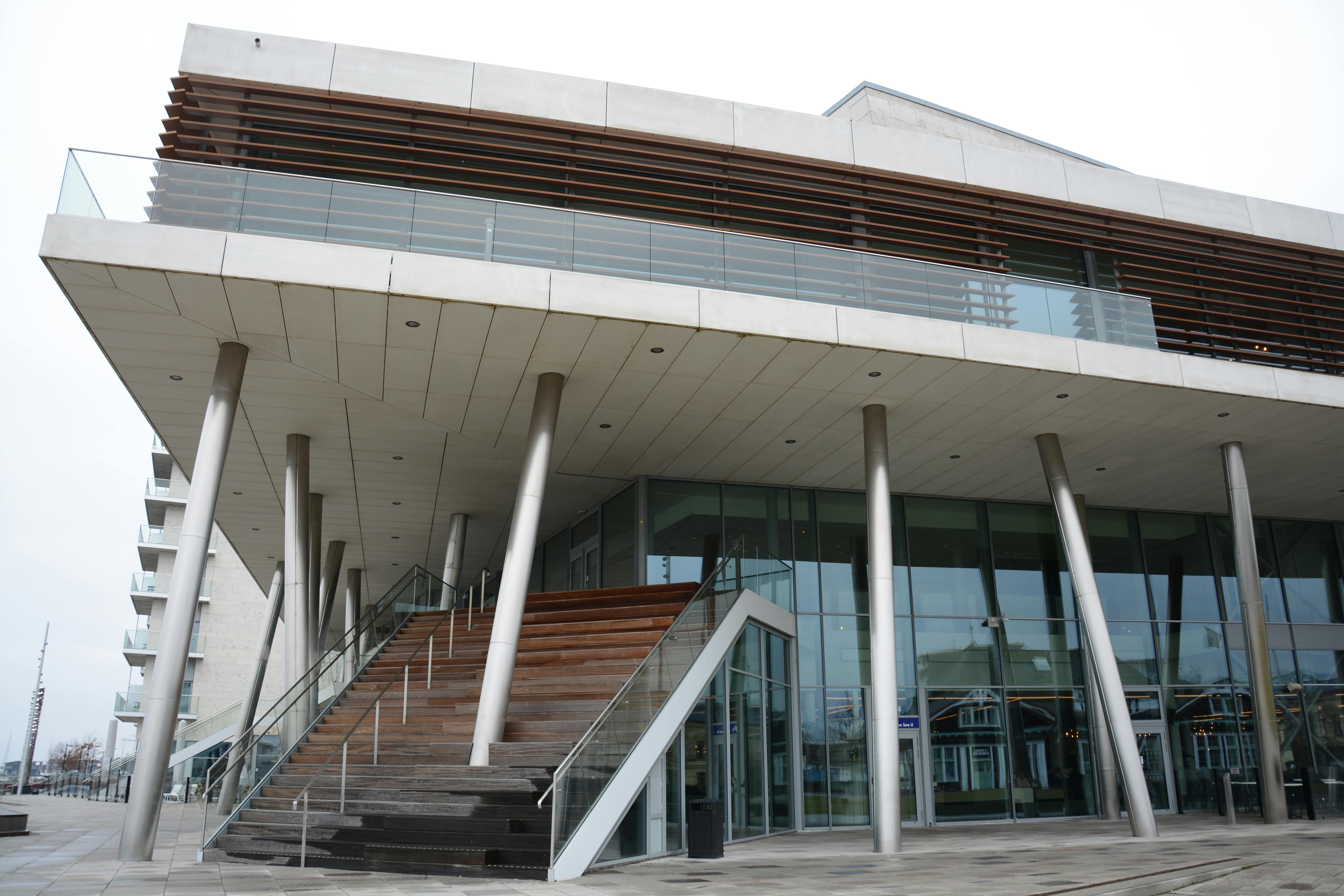 無料 ガラス張りのファサードと、階段や柱を備えた洗練された建築様式が特徴的な現代的な建物。 写真素材