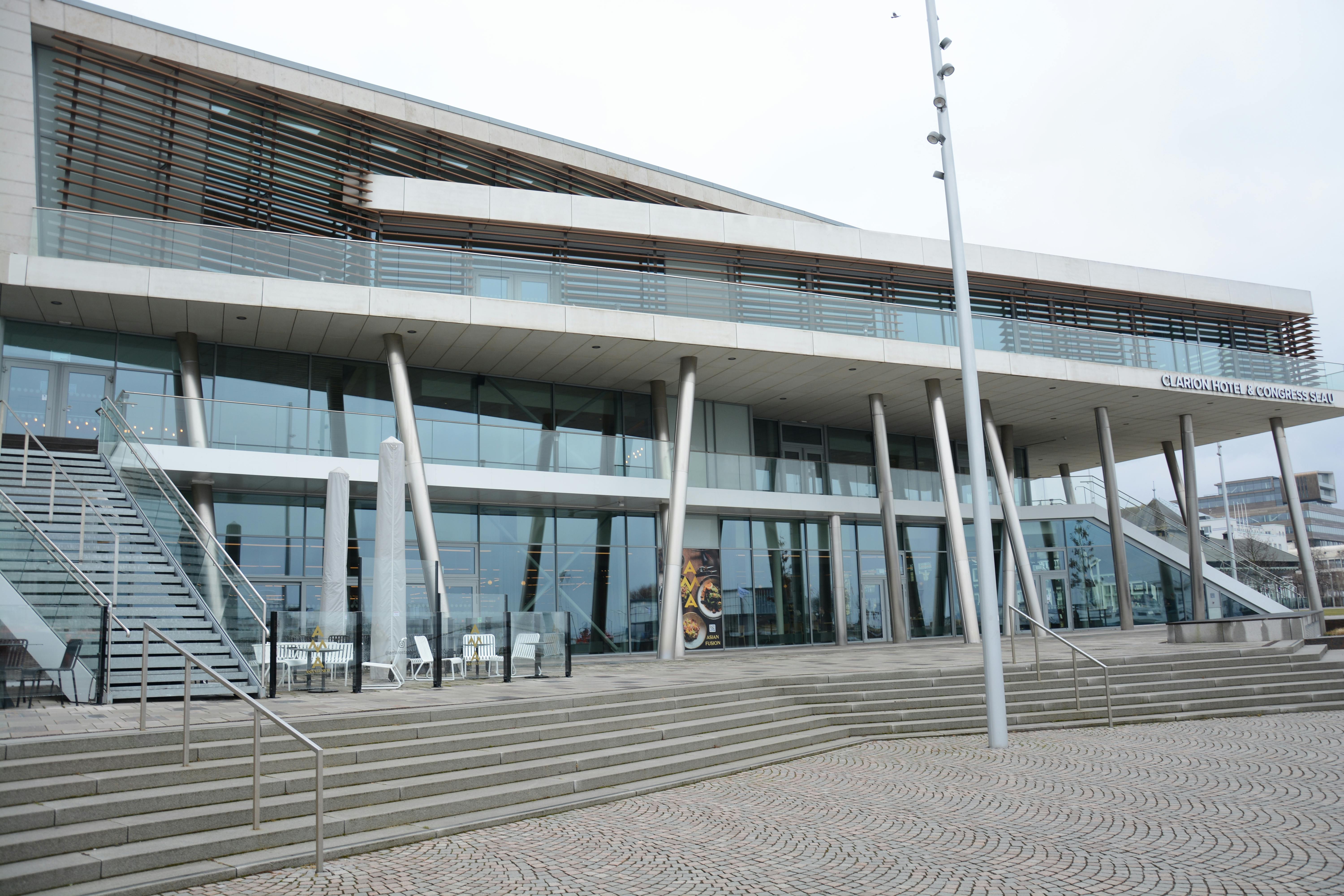 Bezpłatne Widok frontowy Clarion Hotel & Congress z jego nowoczesną architekturą i szklaną fasadą. Zdjęcie z galerii