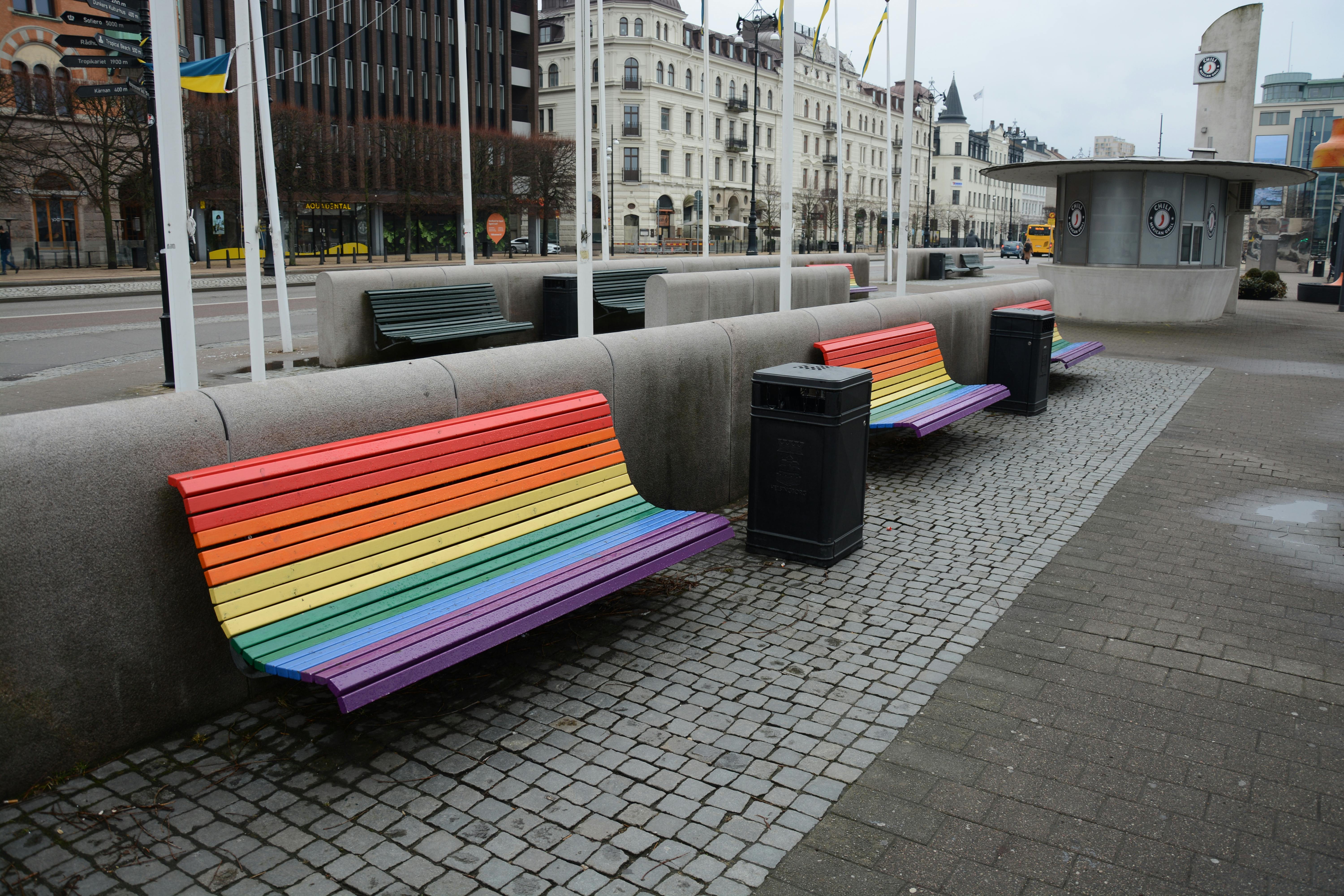Free Colorful rainbow benches in a city street setting, symbolizing diversity and inclusion. Stock Photo