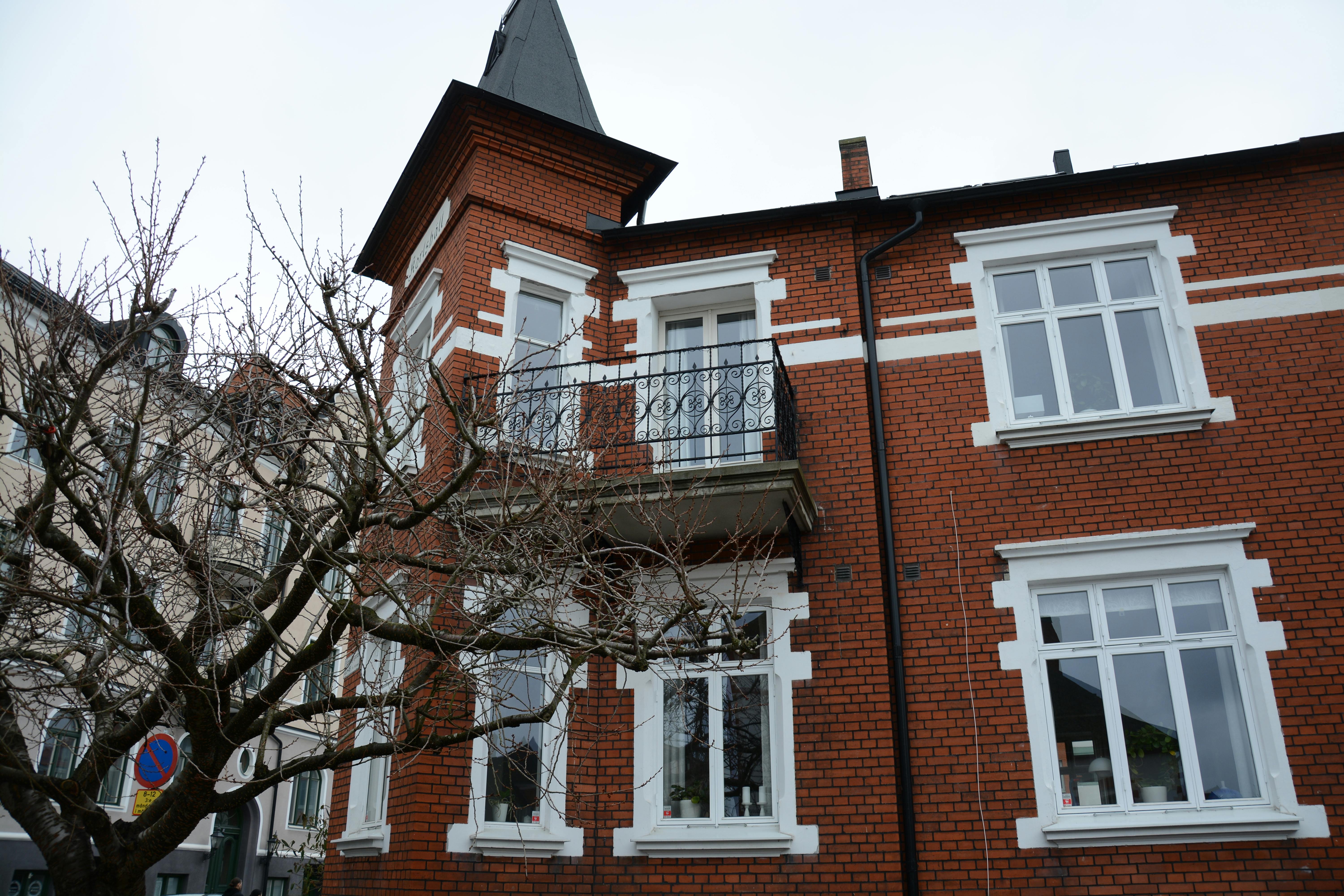 Gratis En smuk rød murstensbygning med dekorativ balkon og golde trægrene om vinteren. Lagerfoto