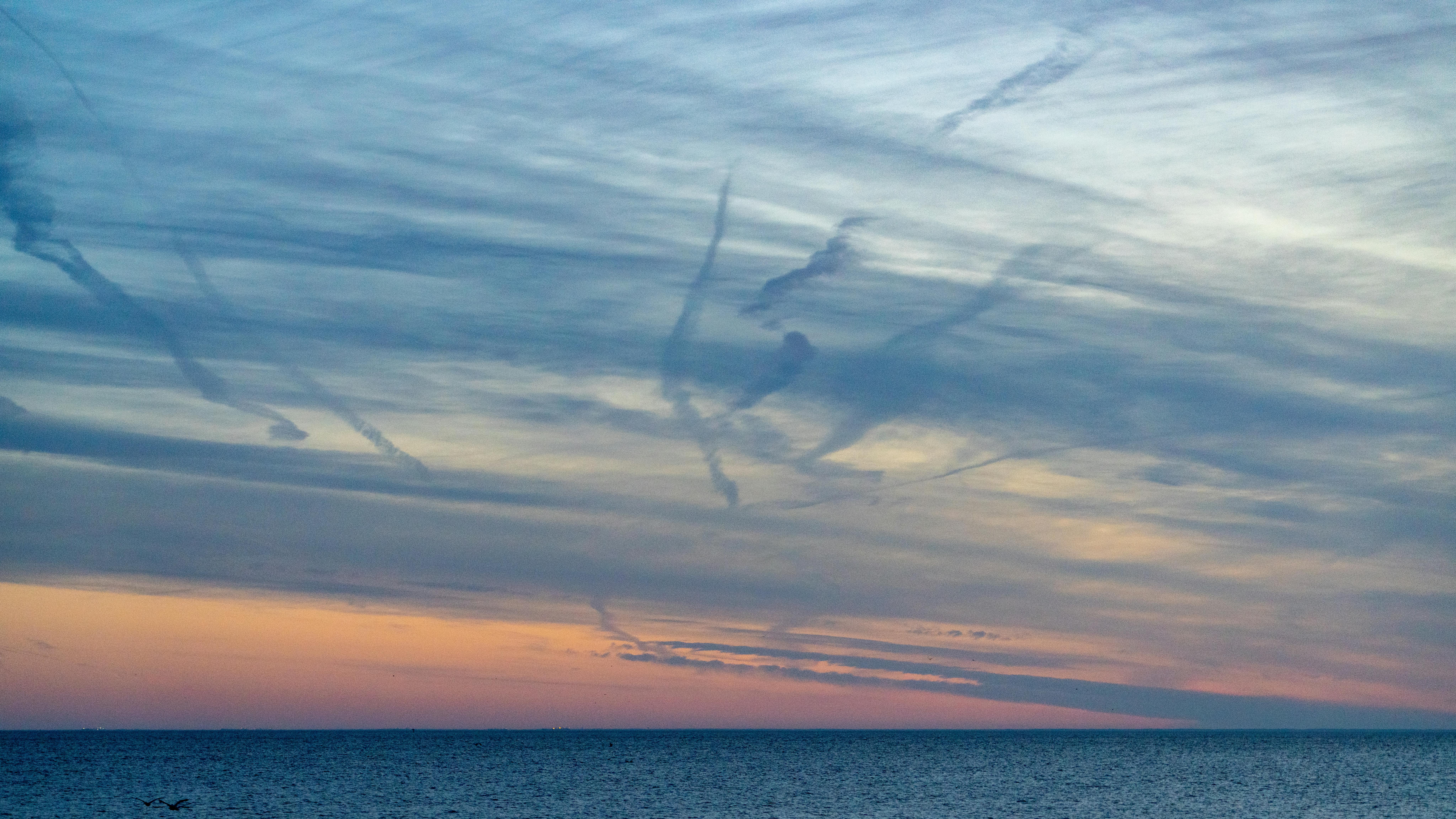 Gratuit O priveliște liniștită a oceanului în timpul apusului, cu nori vibranți și cer colorat, creând o atmosferă senină. Fotografie de stoc