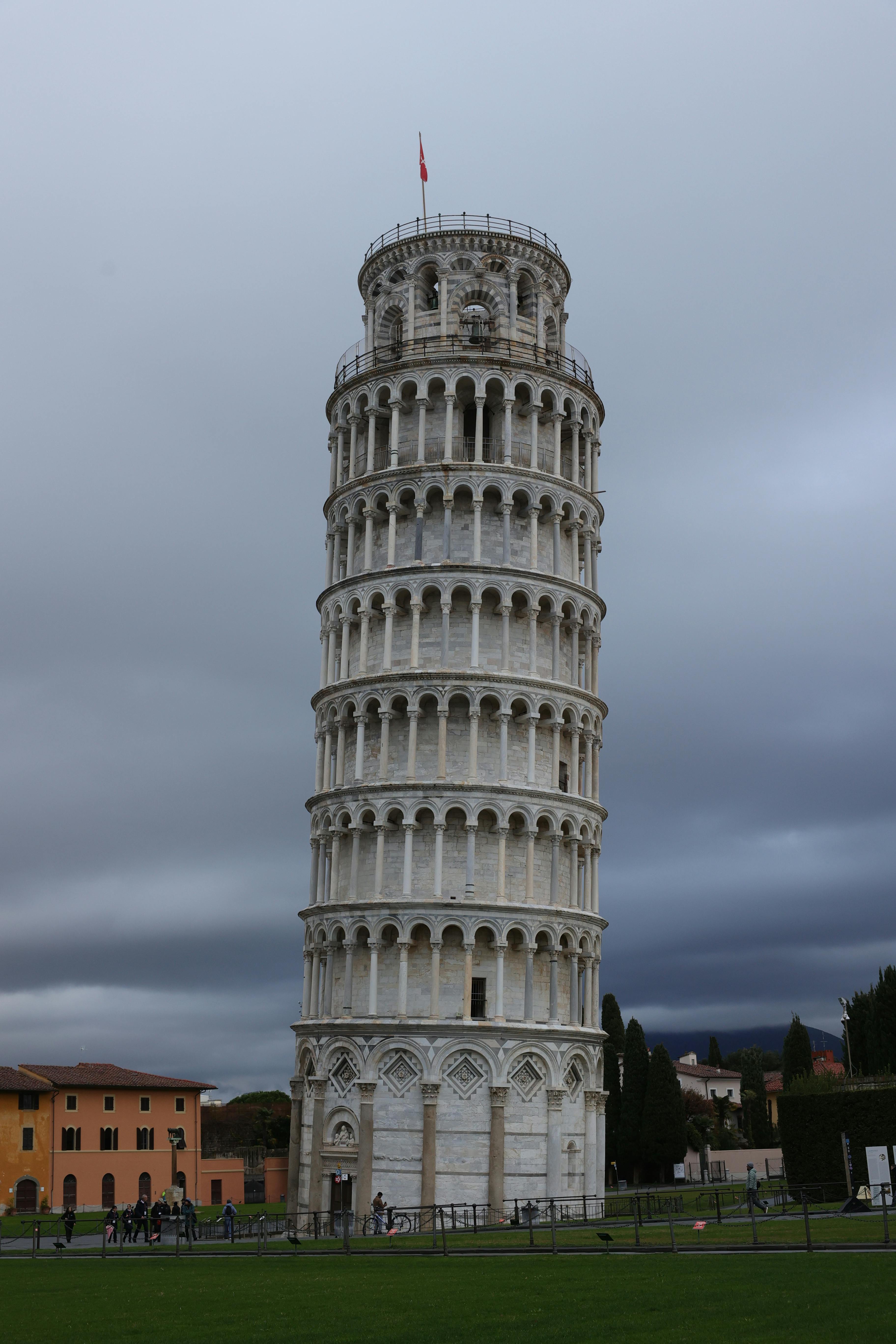 ingyenes Az ikonikus pisai ferde torony magasodik a drámai felhős égbolt előtt Olaszországban. Stockfotó