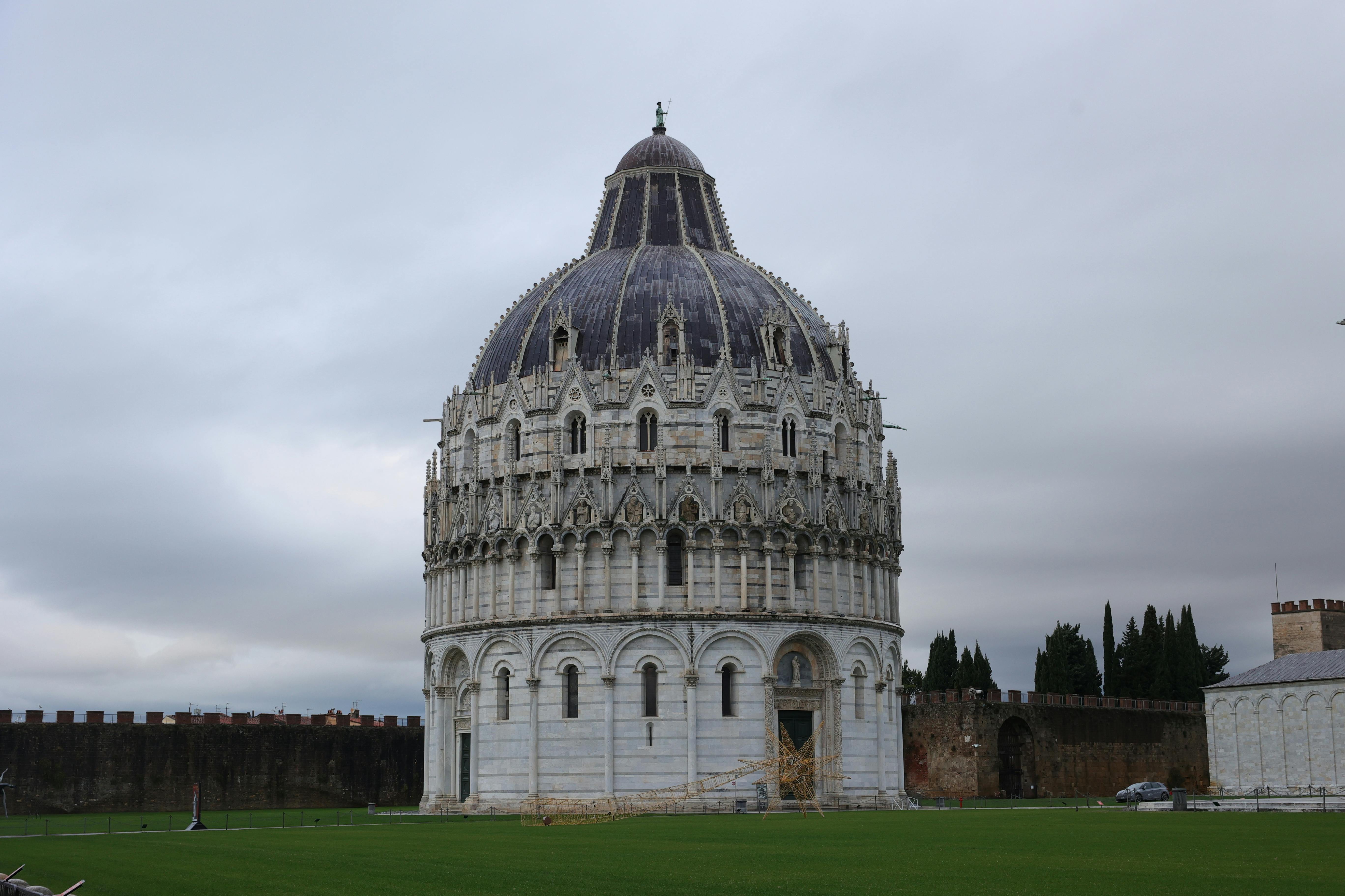 무료 피사의 기적 광장에 있는 피사 세례당이 흐린 하늘을 배경으로 로마네스크 건축 양식을 뽐내고 있다. 스톡 사진