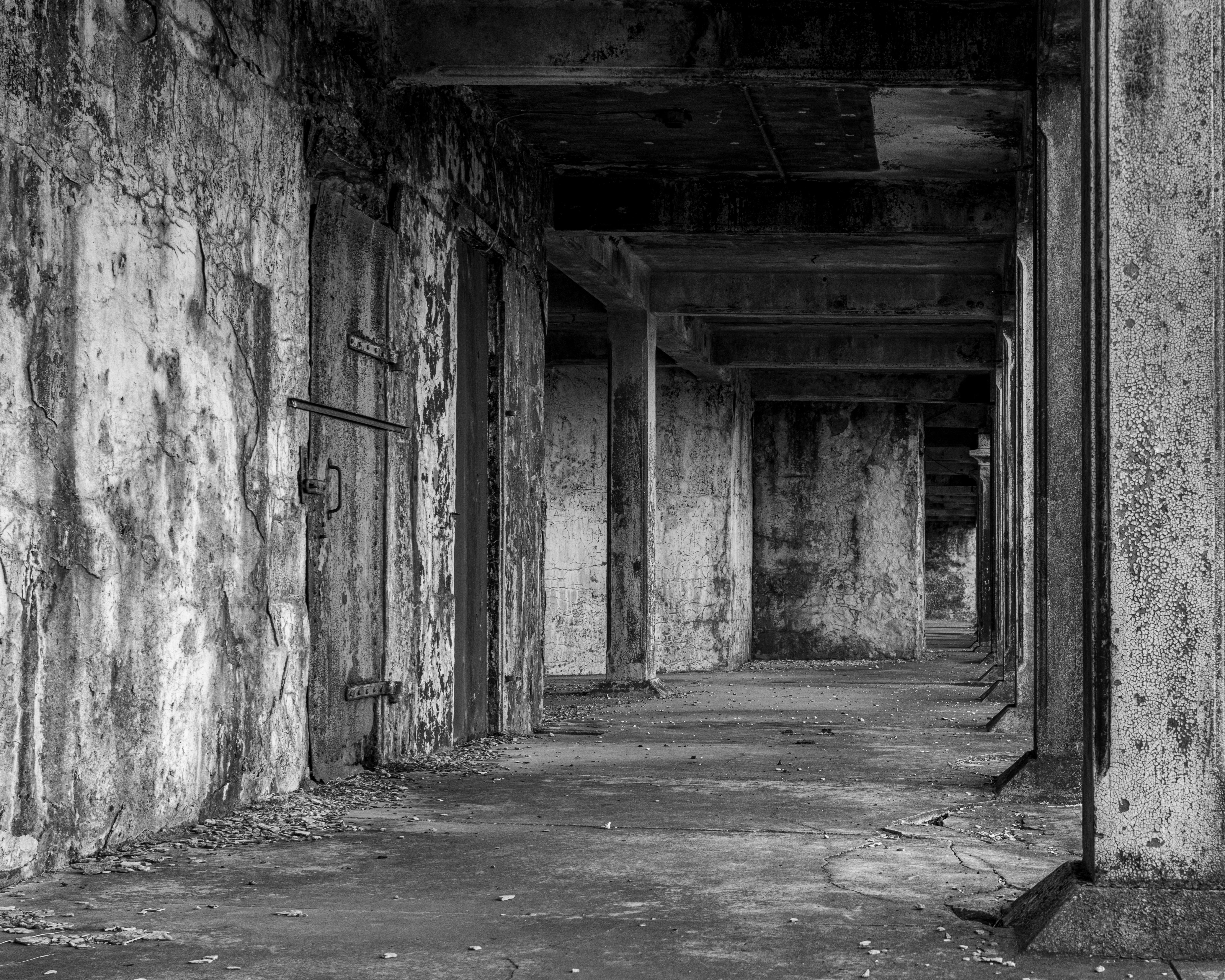 бесплатная Черно-белая фотография заброшенного промышленного коридора с бетонными стенами и колоннами. Стоковое фото