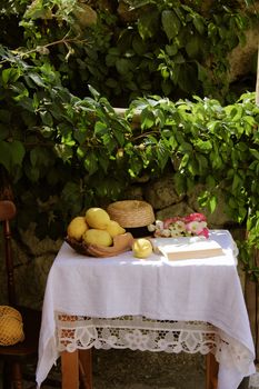 Serene outdoor still life with lemons and hat under lush foliage in Italy.
