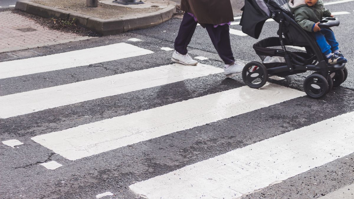 A child in a stroller crossing a zebra crossing in the city. Urban street scene focusing on pedestrian safety.
