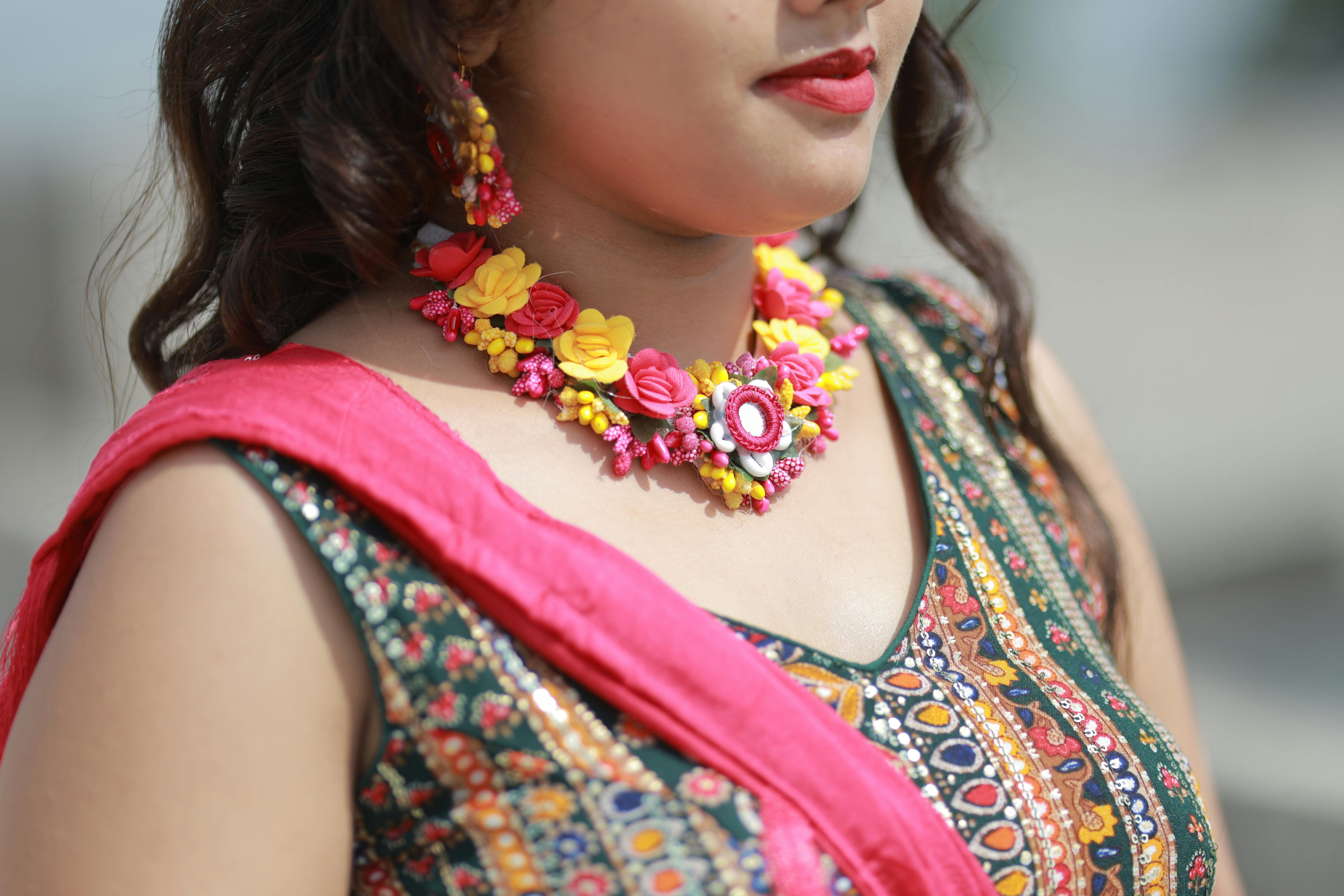 Gratis Primer plano de una mujer con coloridas joyas florales y atuendo tradicional, perfecto para ocasiones festivas. Foto de stock