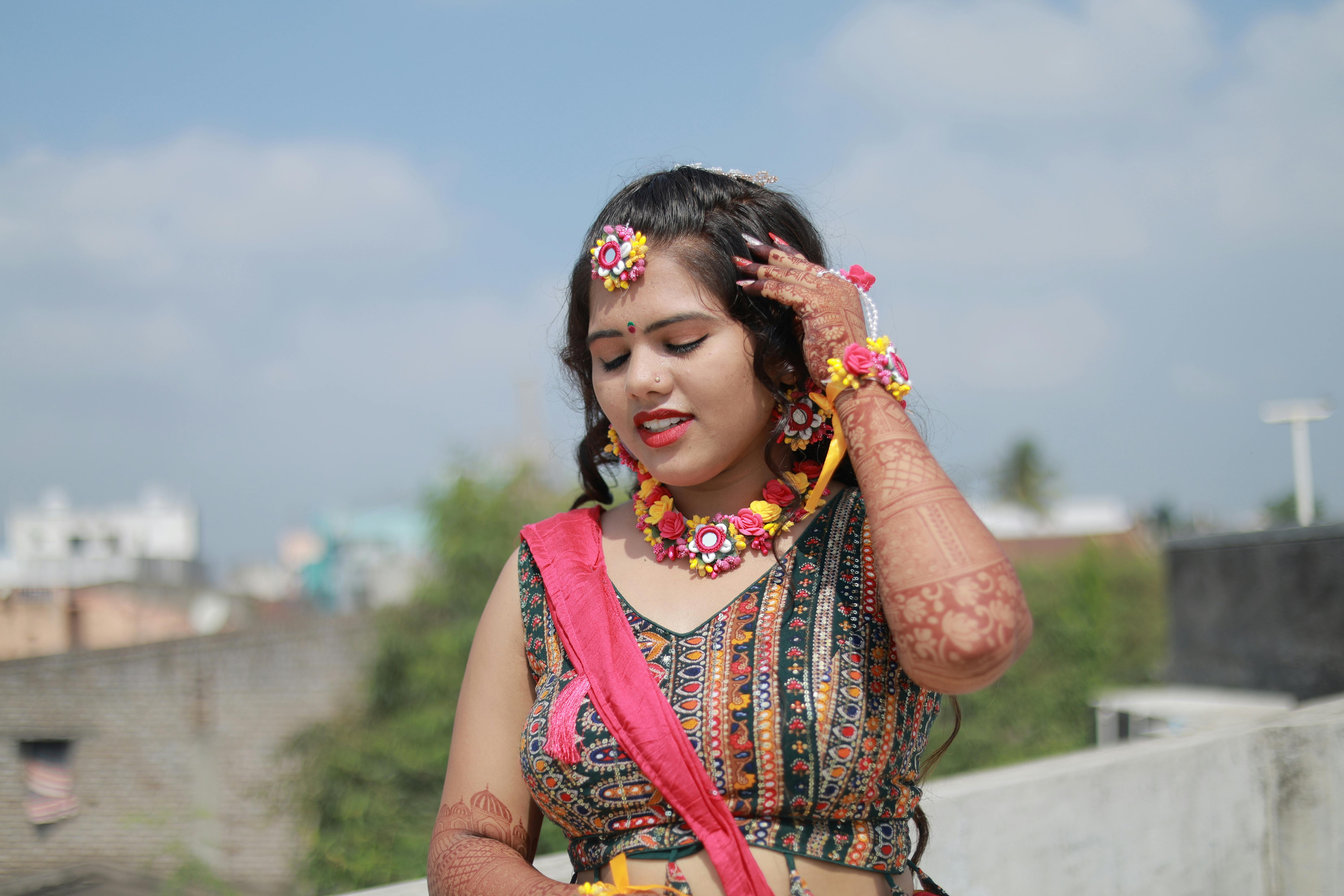 Gratuit Une séance photo de mariée en extérieur mettant en scène une femme adulte en tenue traditionnelle, parée de bijoux floraux et de henné. Photos