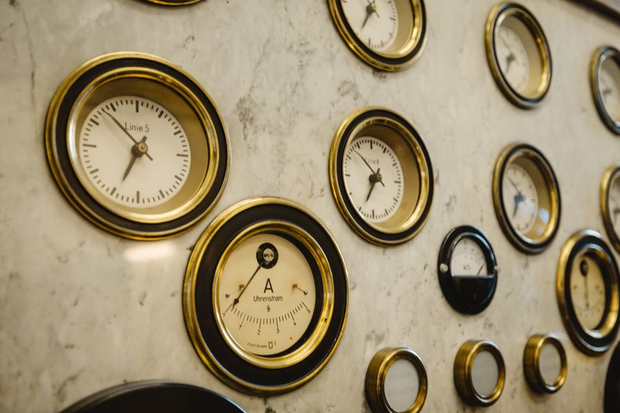 Close-up of vintage brass-rimmed dial gauges mounted on a marble panel.