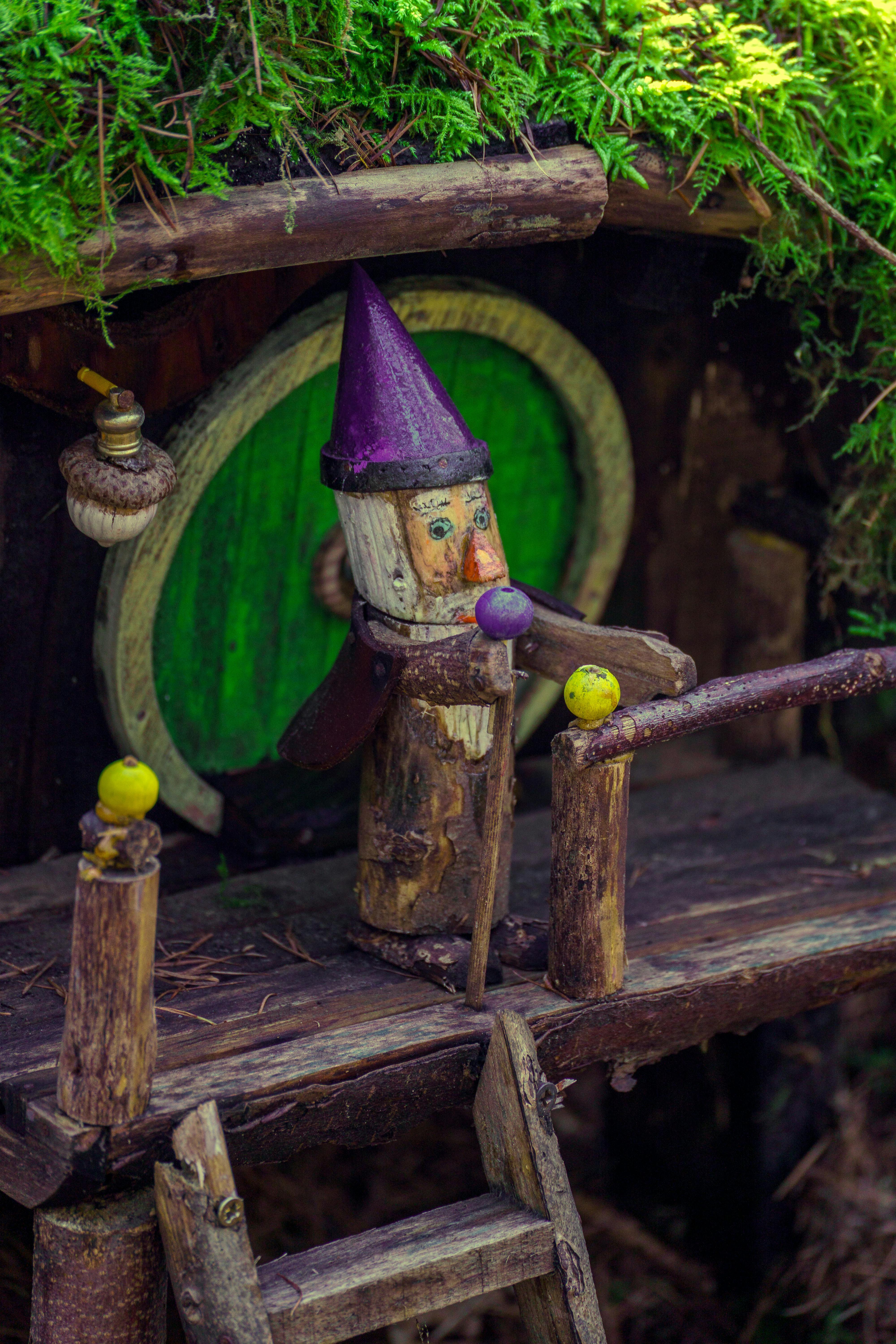 бесплатная Причудливая миниатюрная деревянная хижина с резной фигуркой, утопающая в пышном зеленом мхе. Стоковое фото